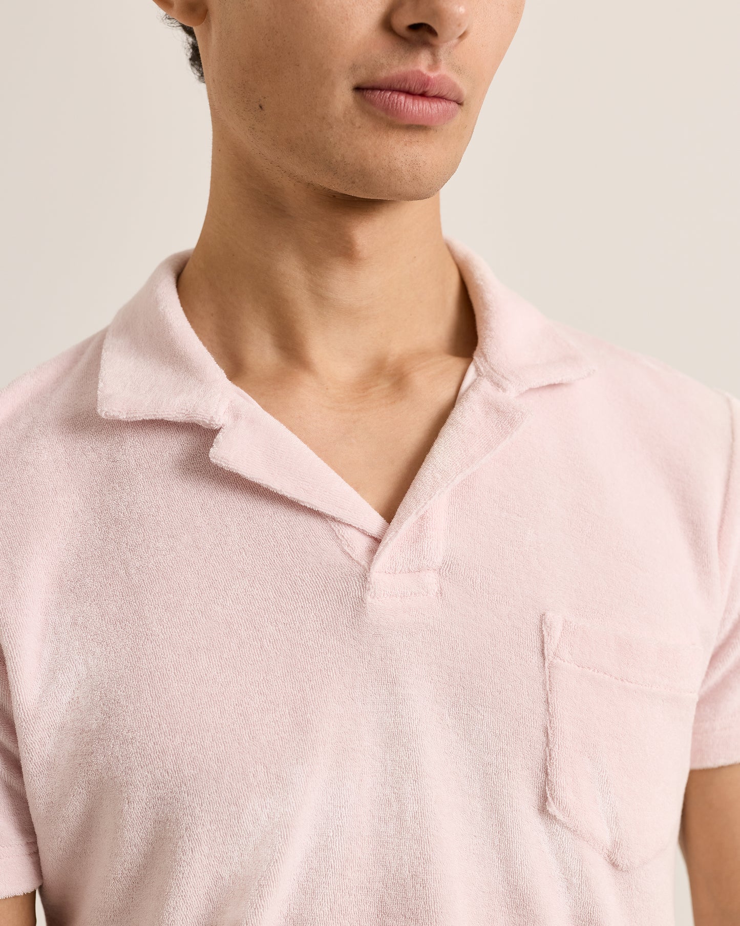 Close-up of a person wearing a light pink polo shirt against a neutral background