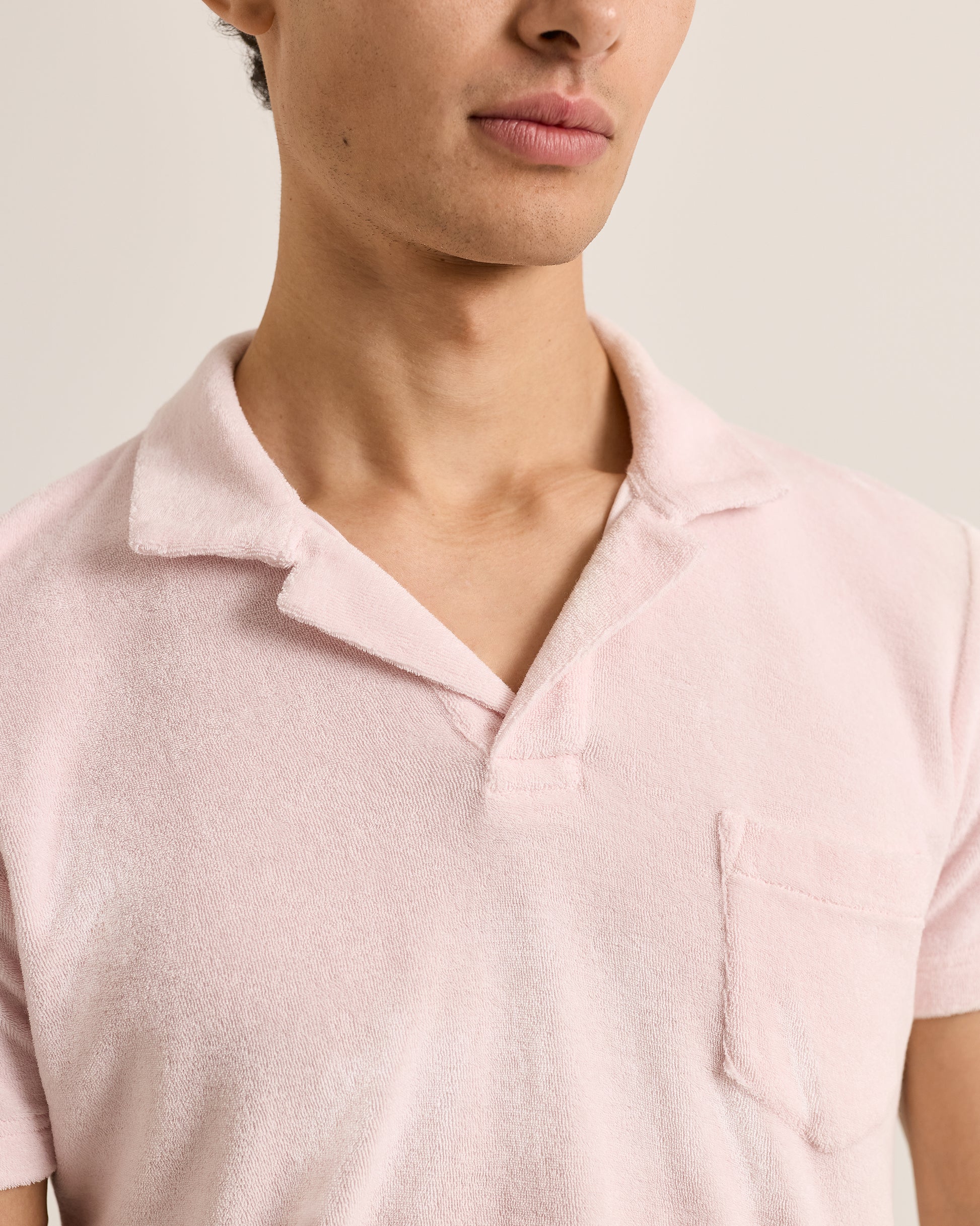 Close-up of a person wearing a light pink polo shirt against a neutral background