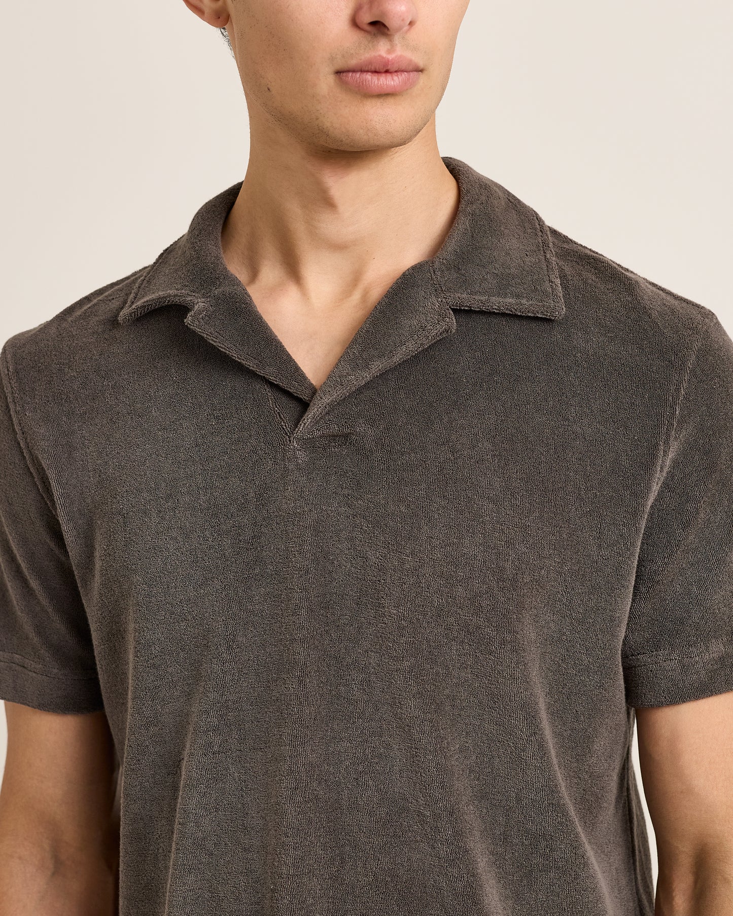 Man wearing a brown polo shirt against a neutral background