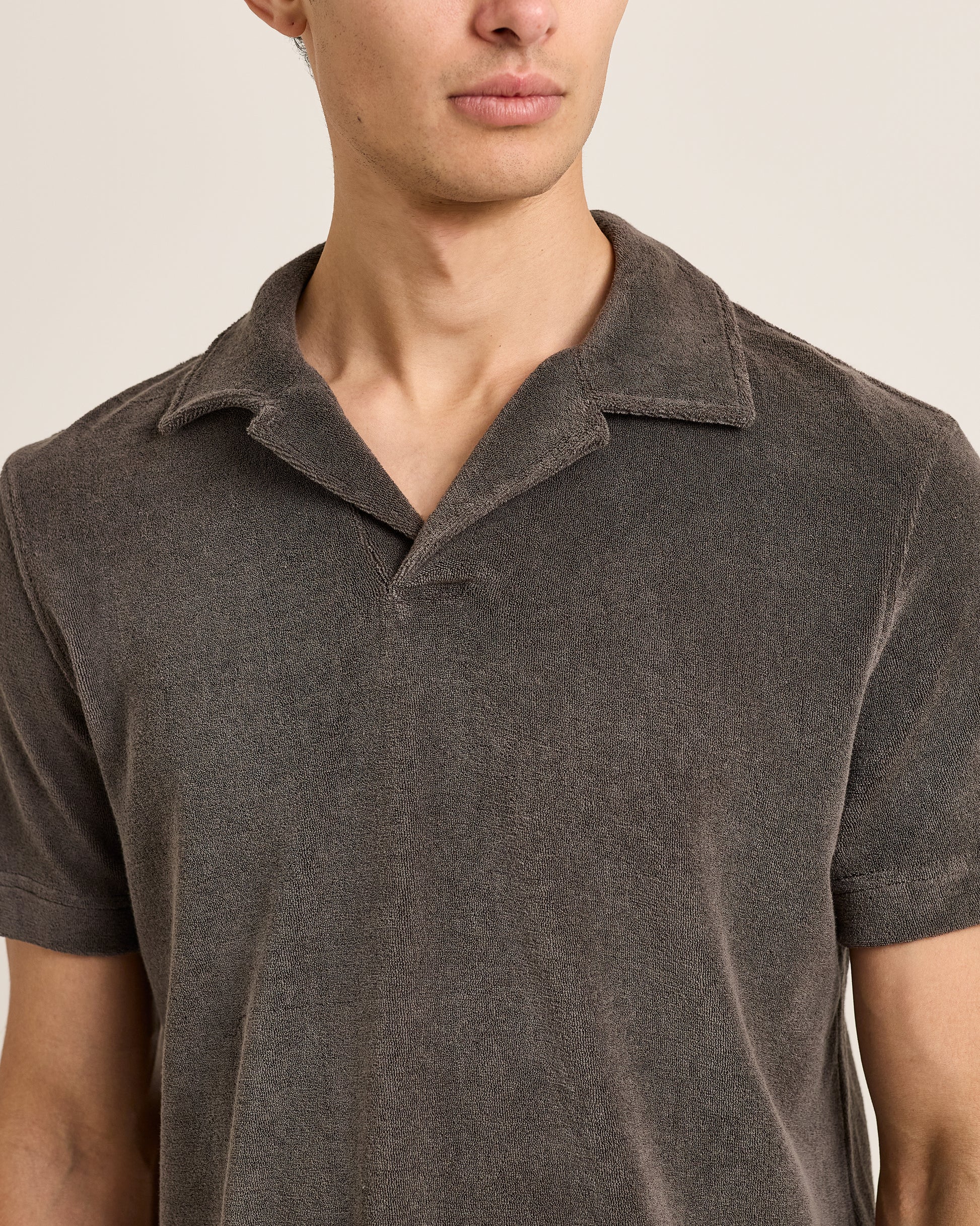 Man wearing a brown polo shirt against a neutral background