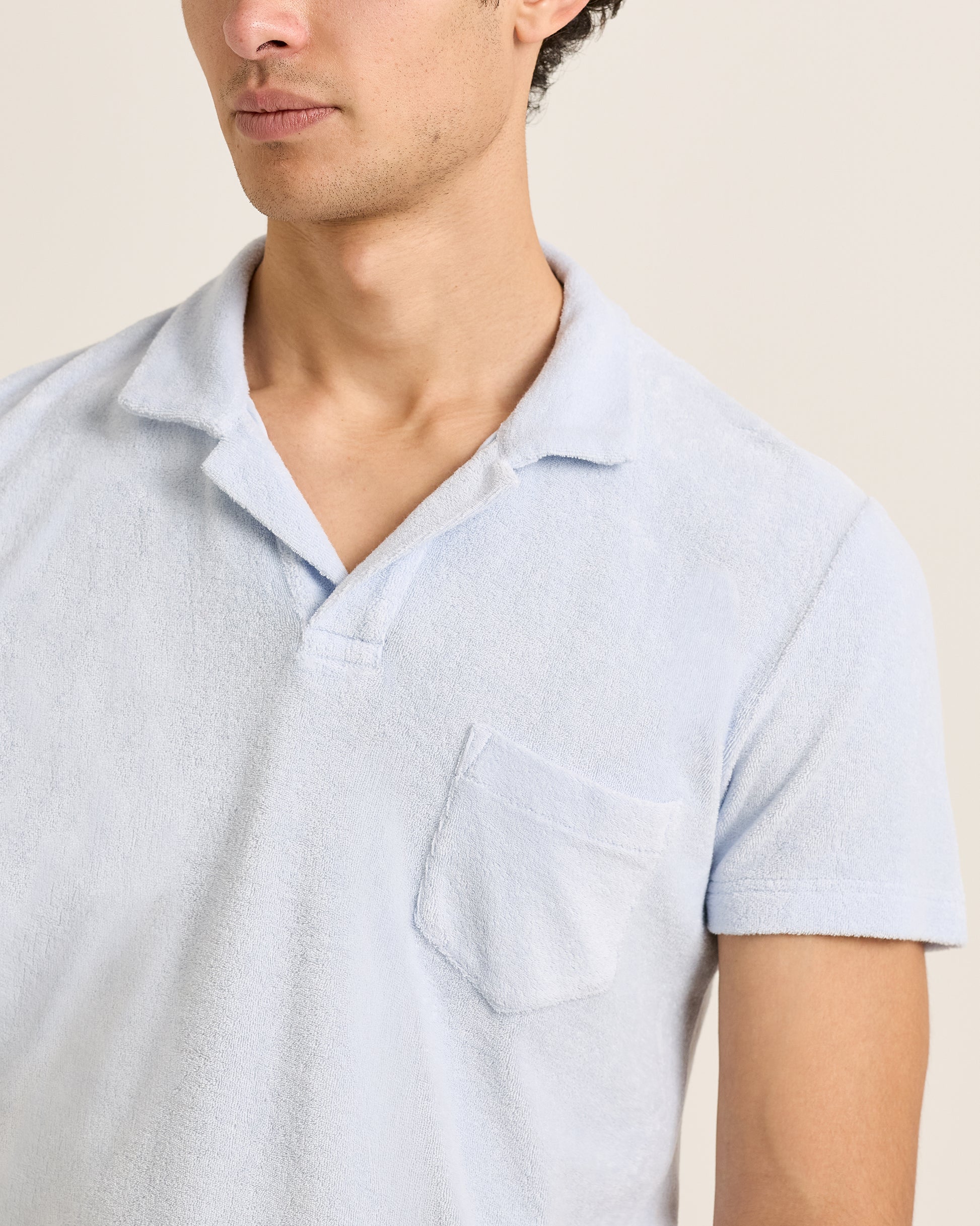 Light blue short-sleeve shirt worn by a person on a beige background