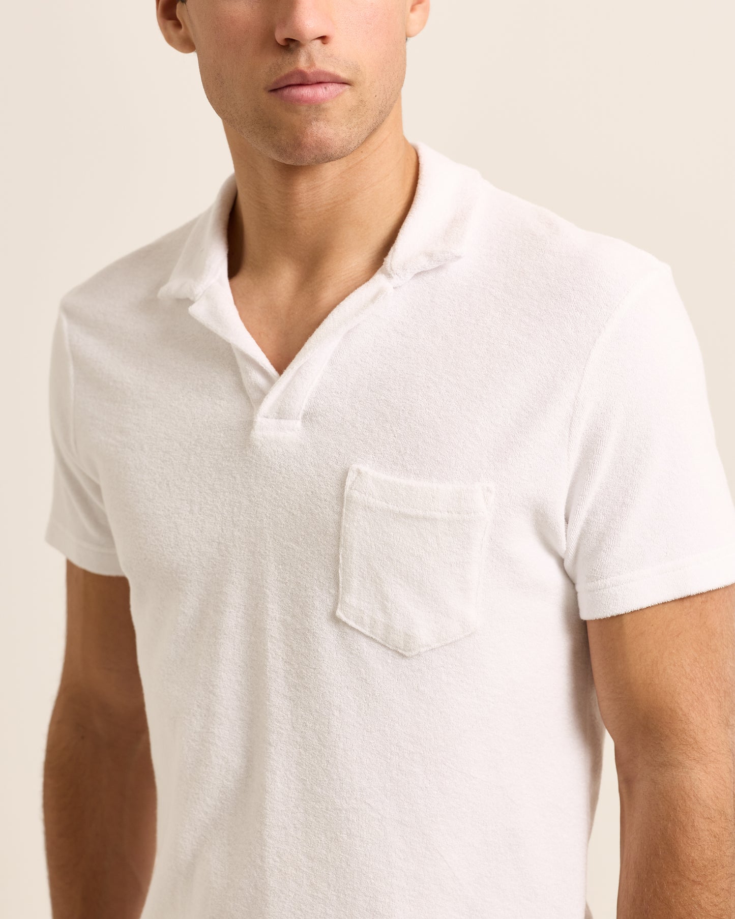 Closeup of man wearing white terry towelling polo shirt with side chest pocket