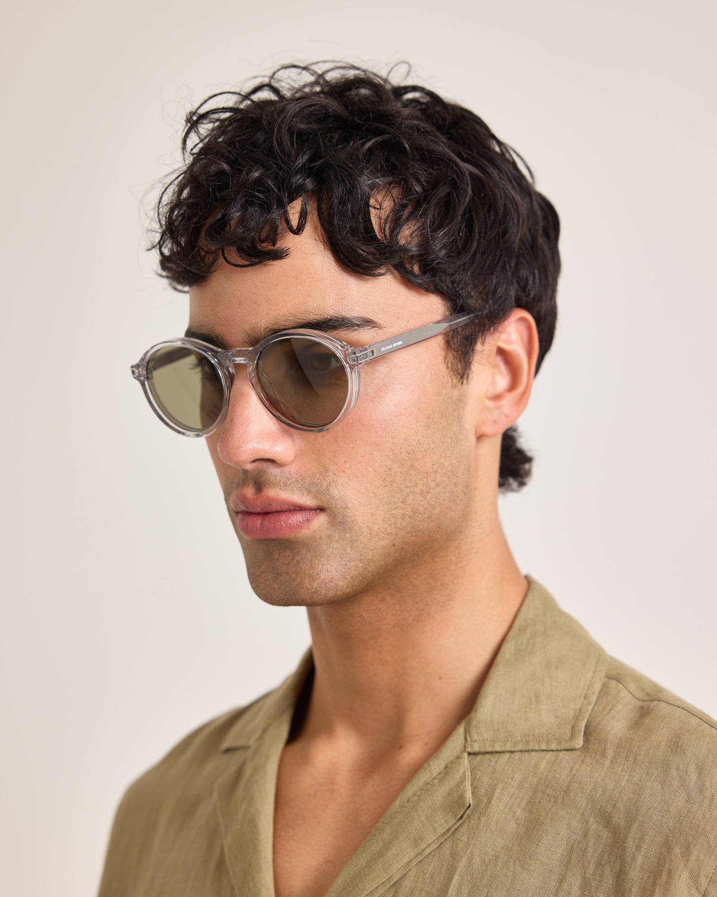 Man wearing sunglasses and a light brown shirt against a plain background