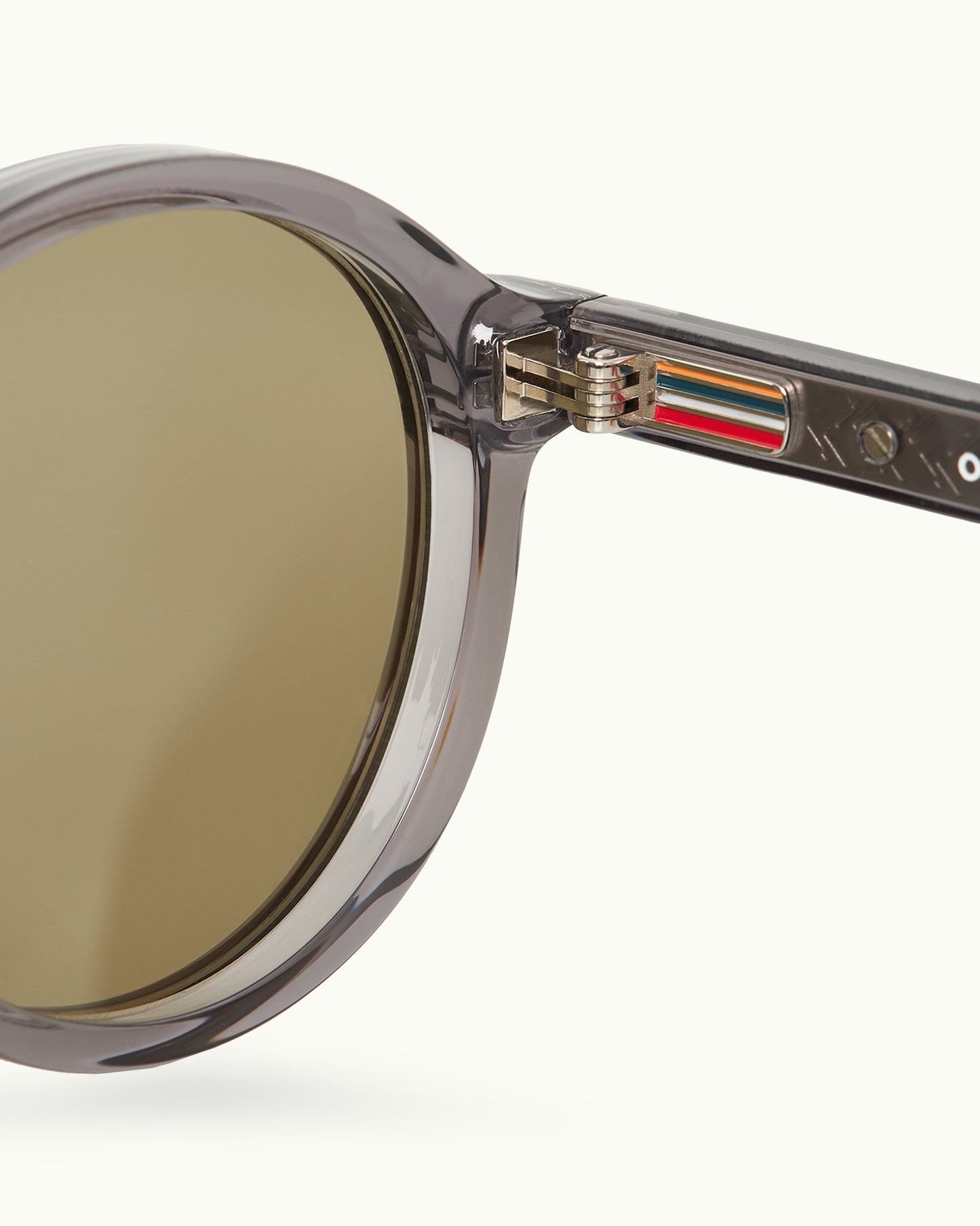 Close-up of a round sunglasses with a clear frame and gold lens on a white background