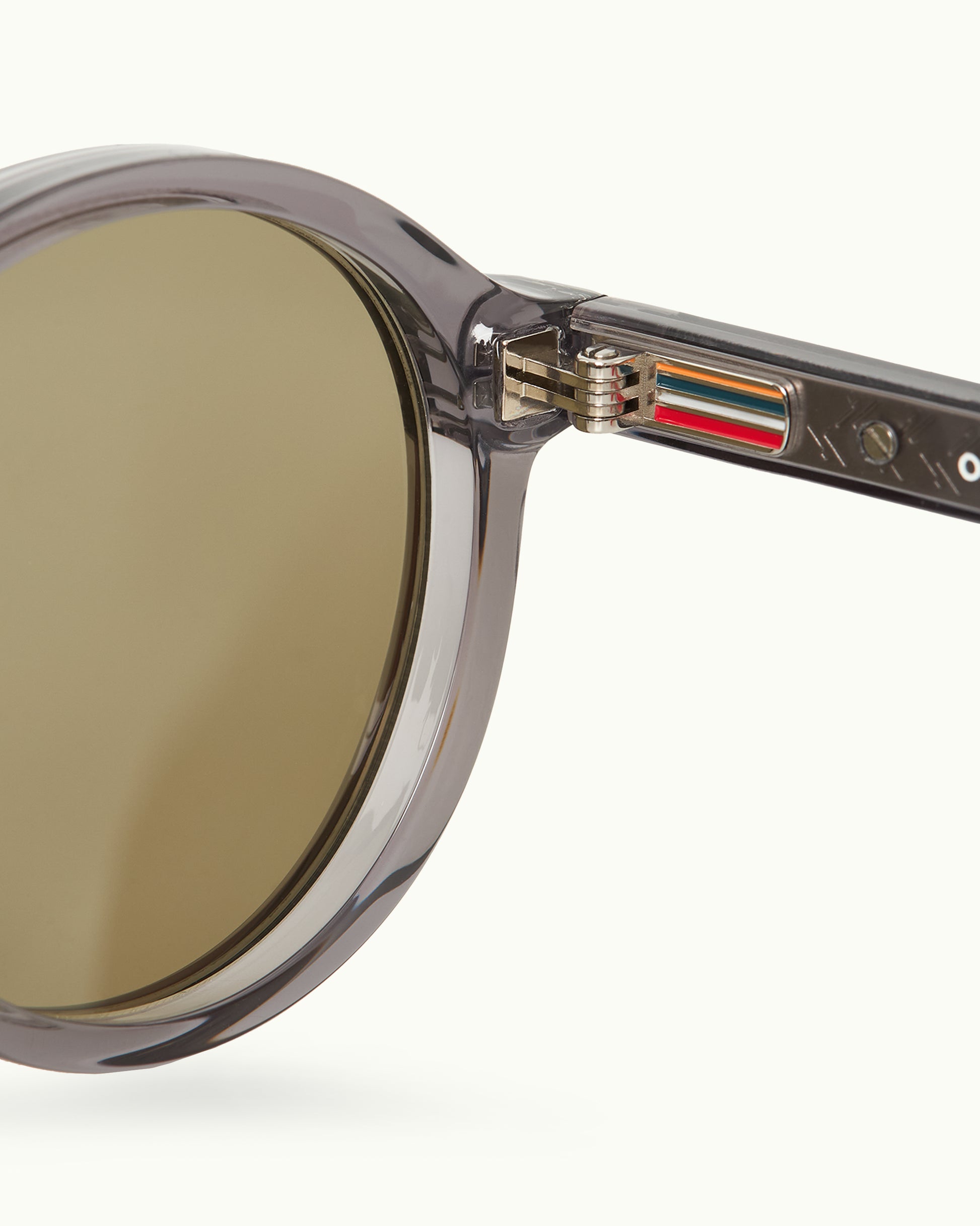 Close-up of a round sunglasses with a clear frame and gold lens on a white background