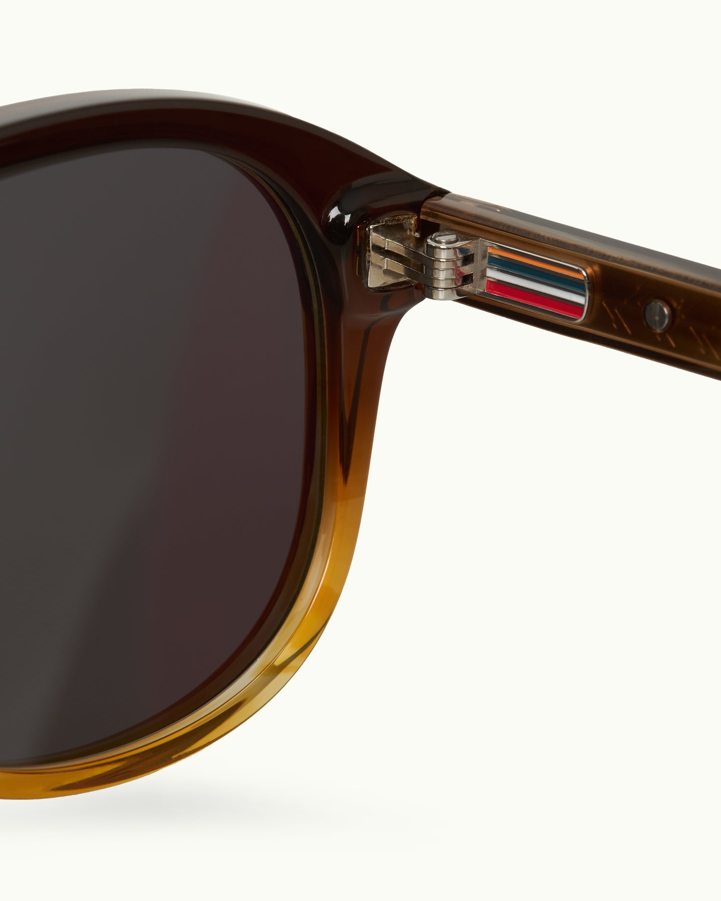 Close-up of a brown sunglasses with a brand logo on a white background