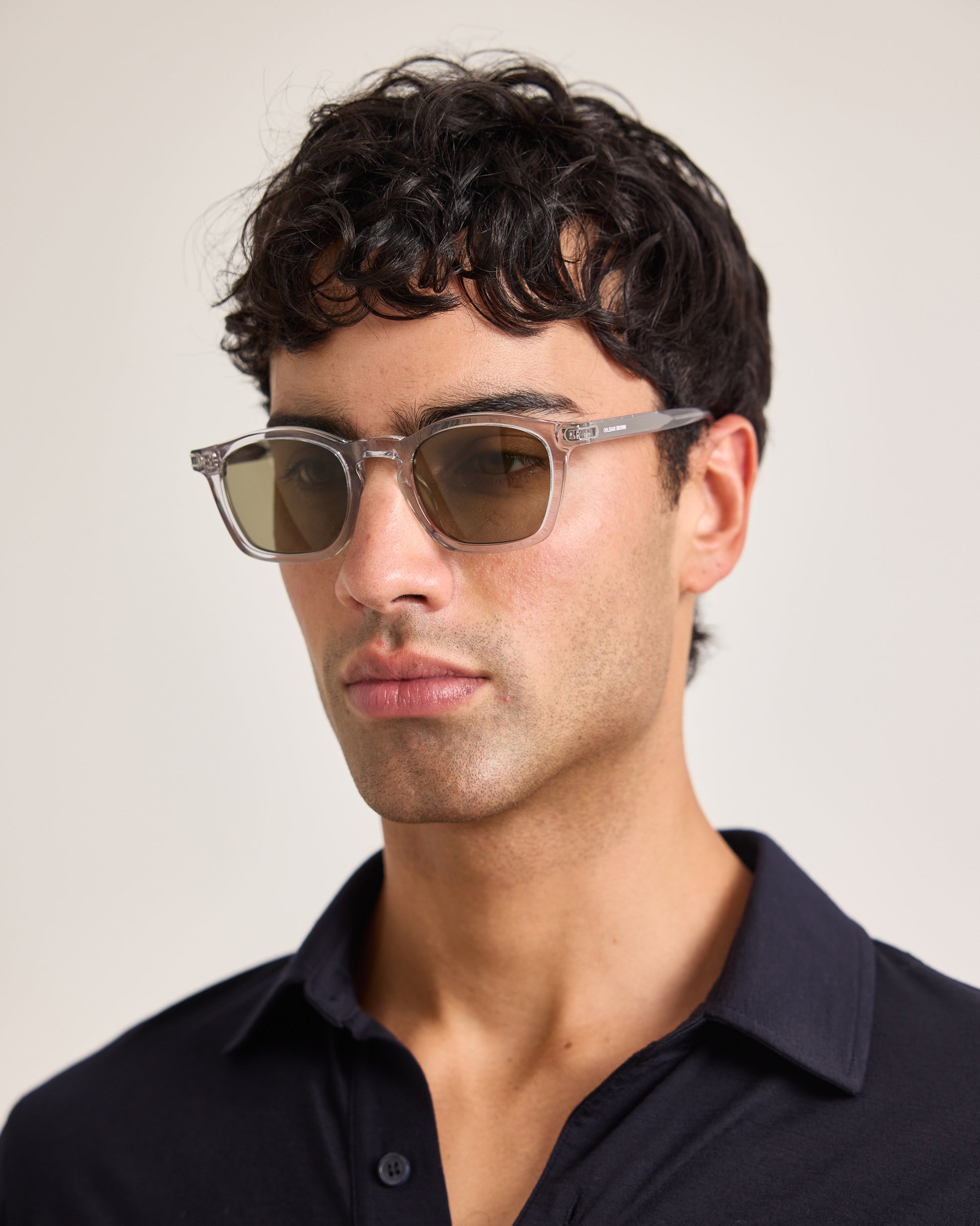 Man wearing sunglasses and a dark shirt against a plain background