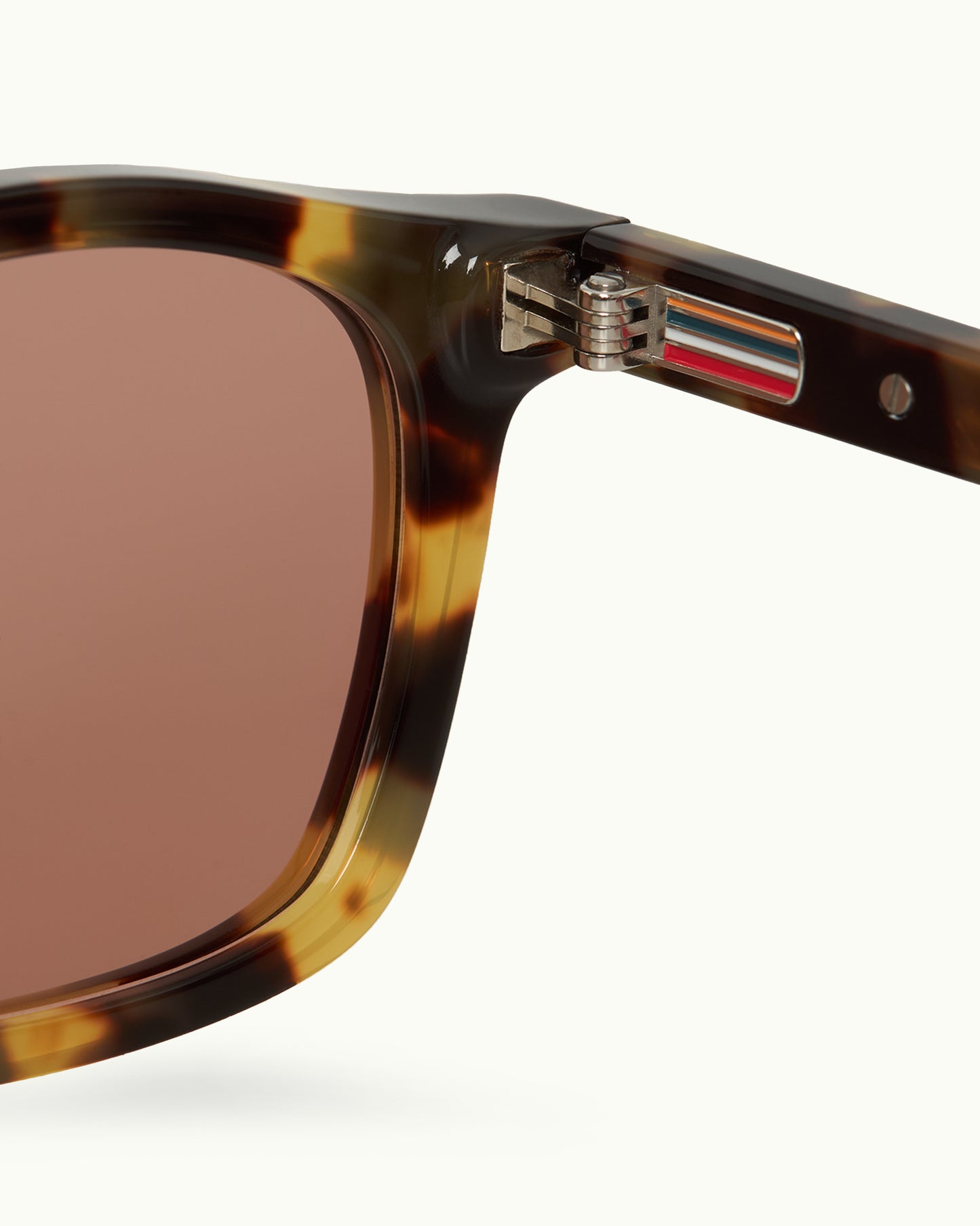 Close-up of sunglasses with tortoiseshell frame and brown lens on a white background