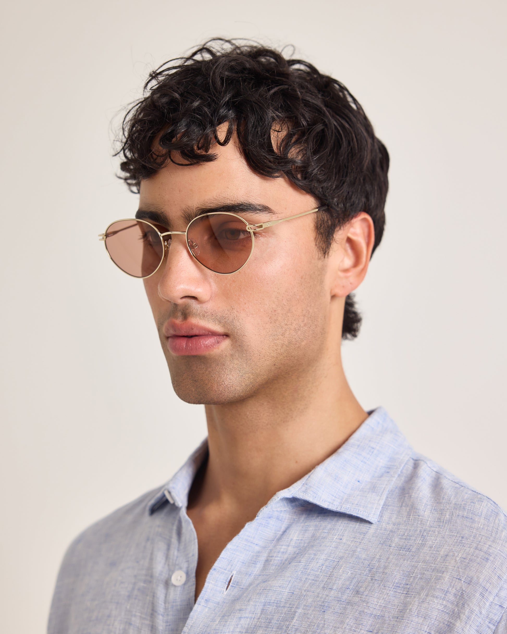 Man wearing sunglasses and a light blue shirt against a plain background