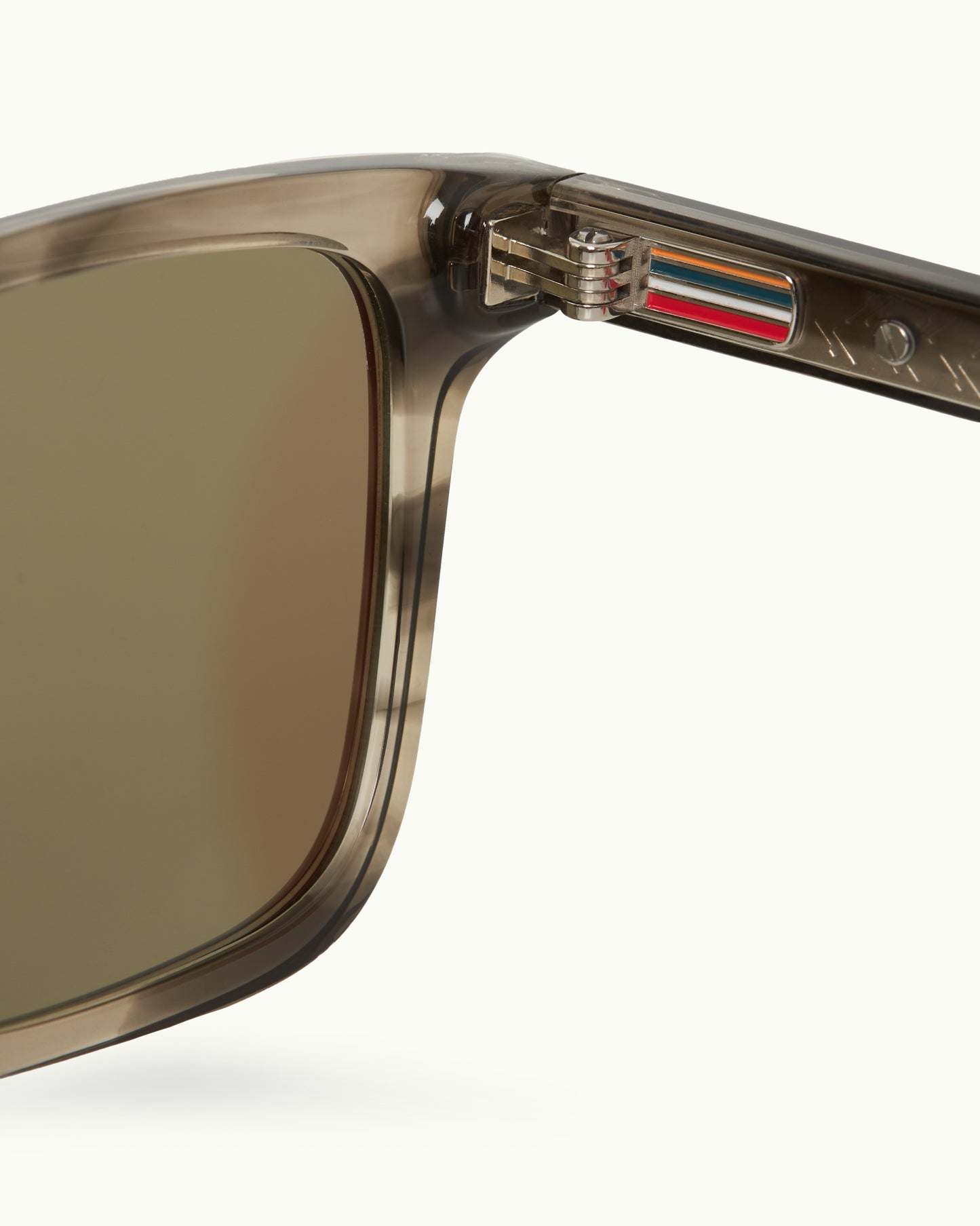 Close-up of a sunglasses with a brand logo on the arm against a white background