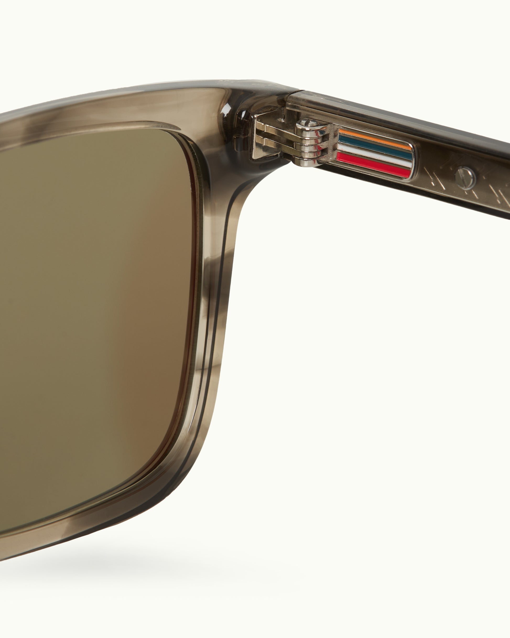 Close-up of a sunglasses with a brand logo on the arm against a white background
