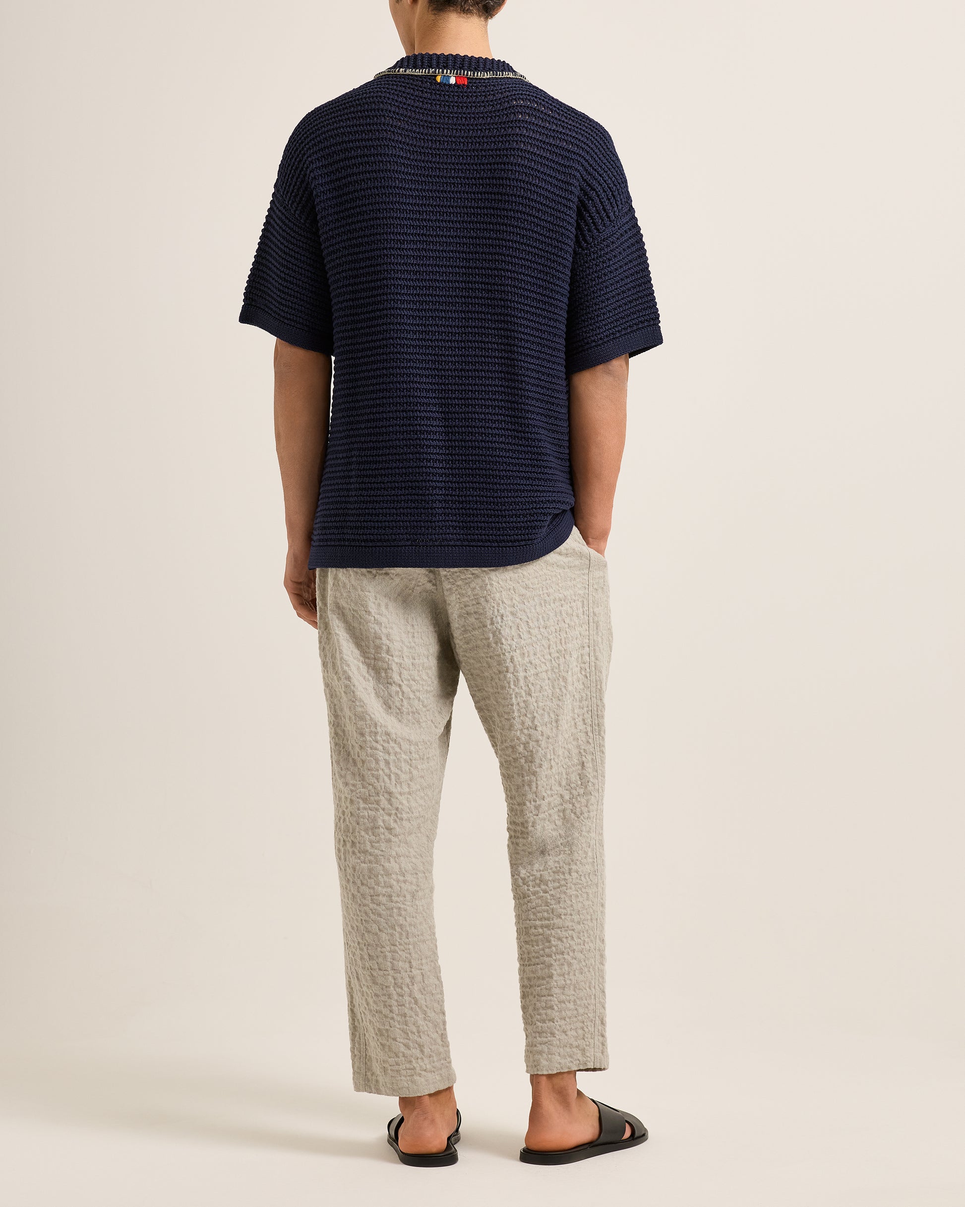 Person wearing a navy striped shirt and light-colored pants on a plain background