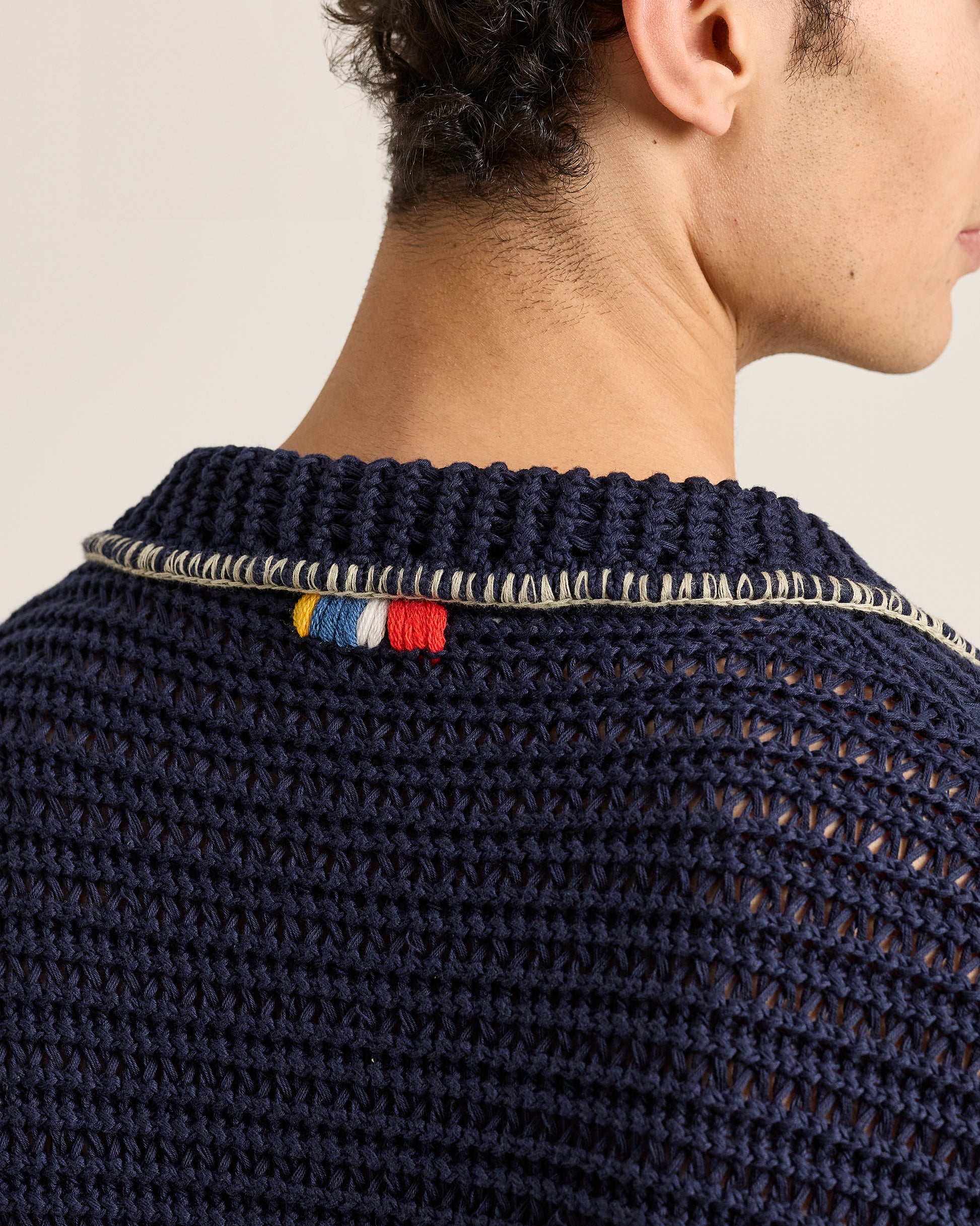 Navy blue knitted sweater with colorful trim on a neutral background
