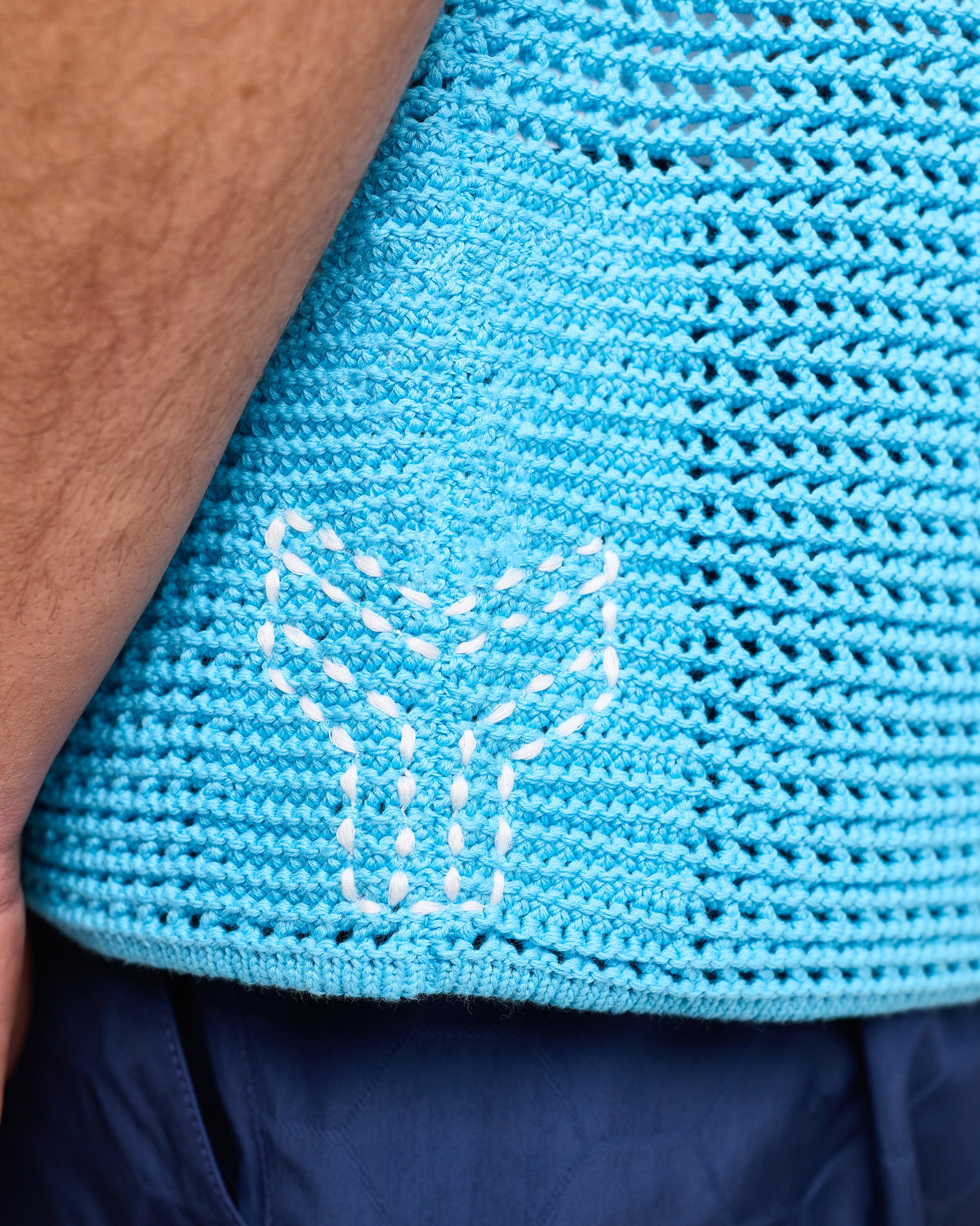Close-up of a blue knitted garment with a white fox design on a person wearing it.