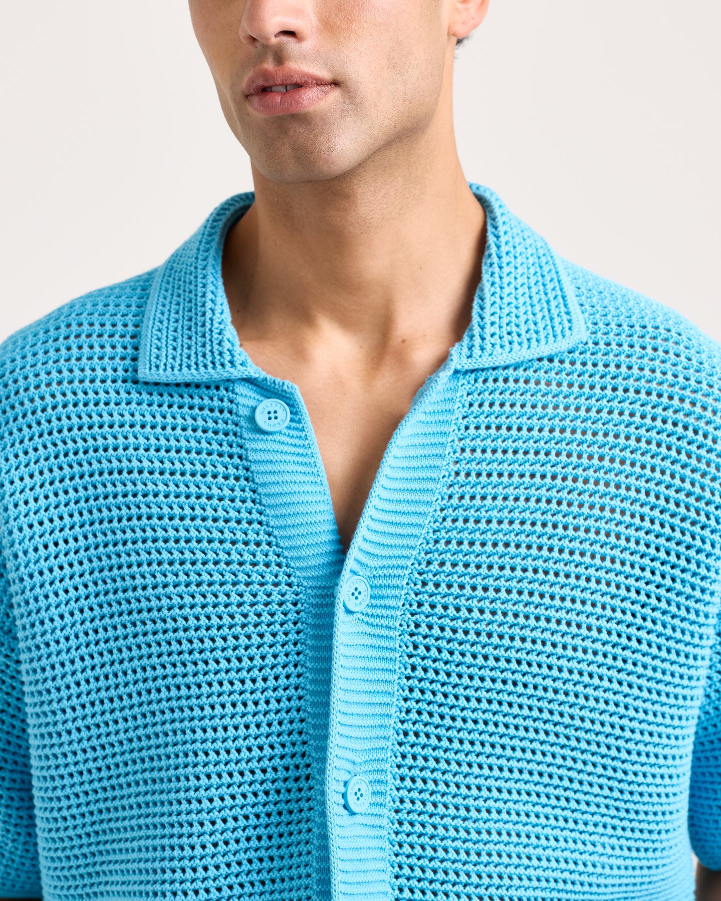 Man wearing a blue textured shirt against a light background