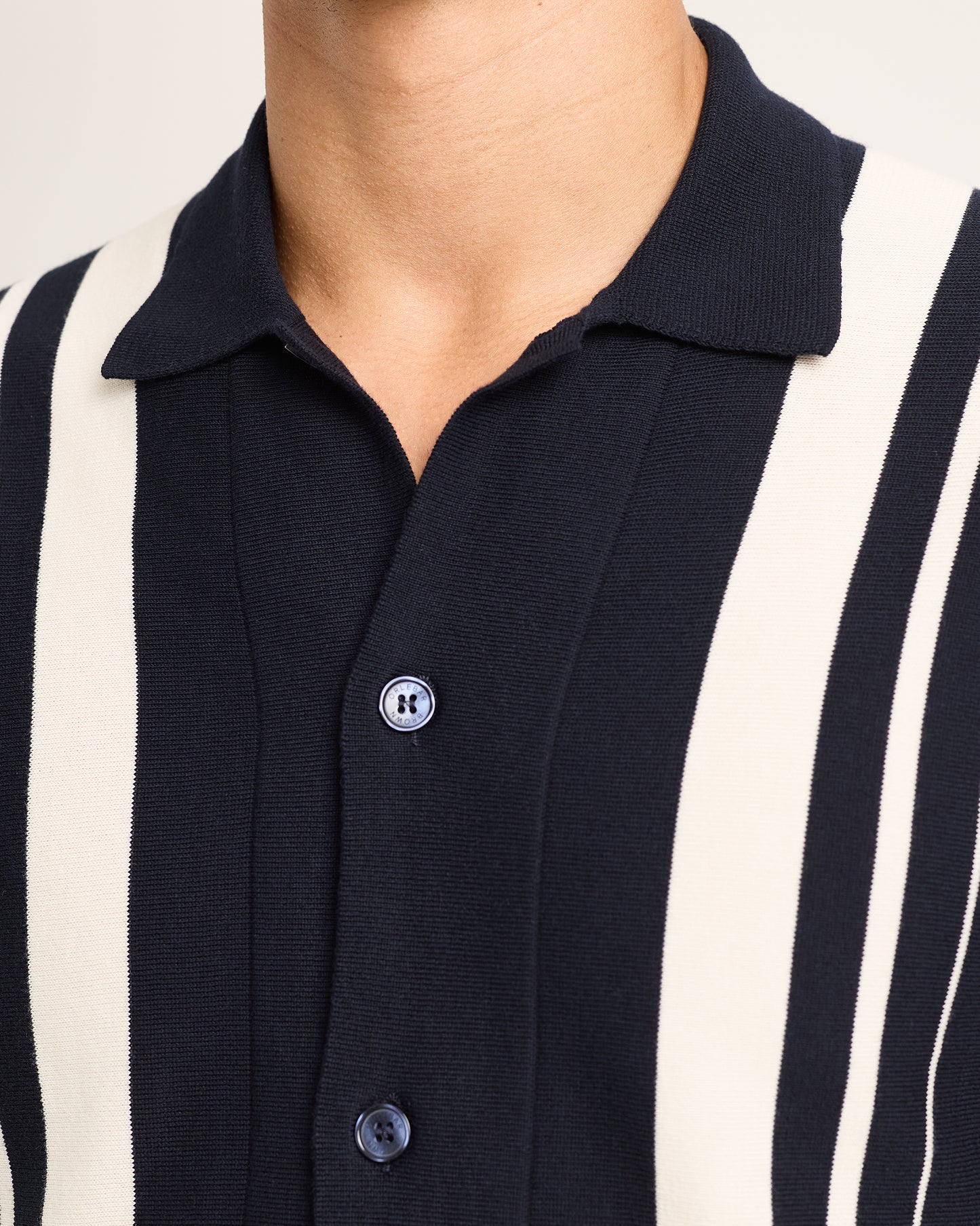 Close-up of navy and white striped shirt with button details on a white background