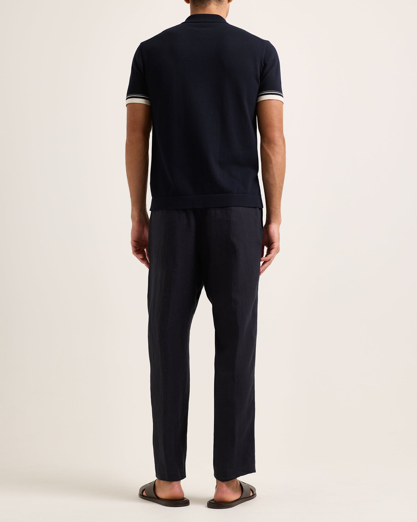 Person wearing a navy blue outfit with white trim on a plain background