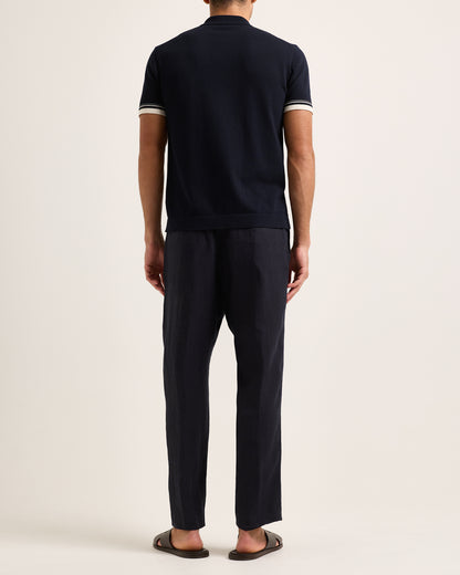 Person wearing a navy blue outfit with white trim on a plain background