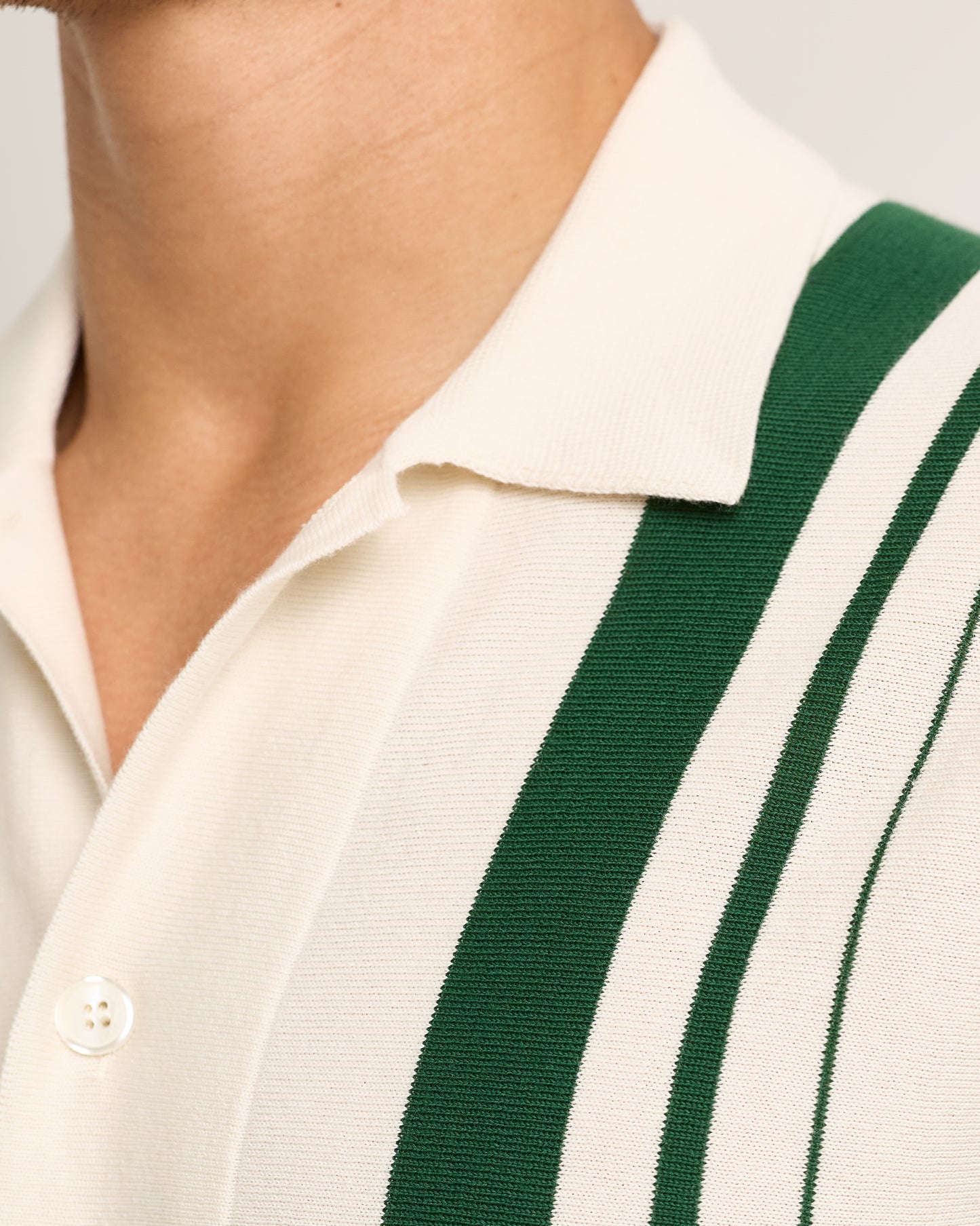 Close-up of a person wearing a white shirt with green stripes.