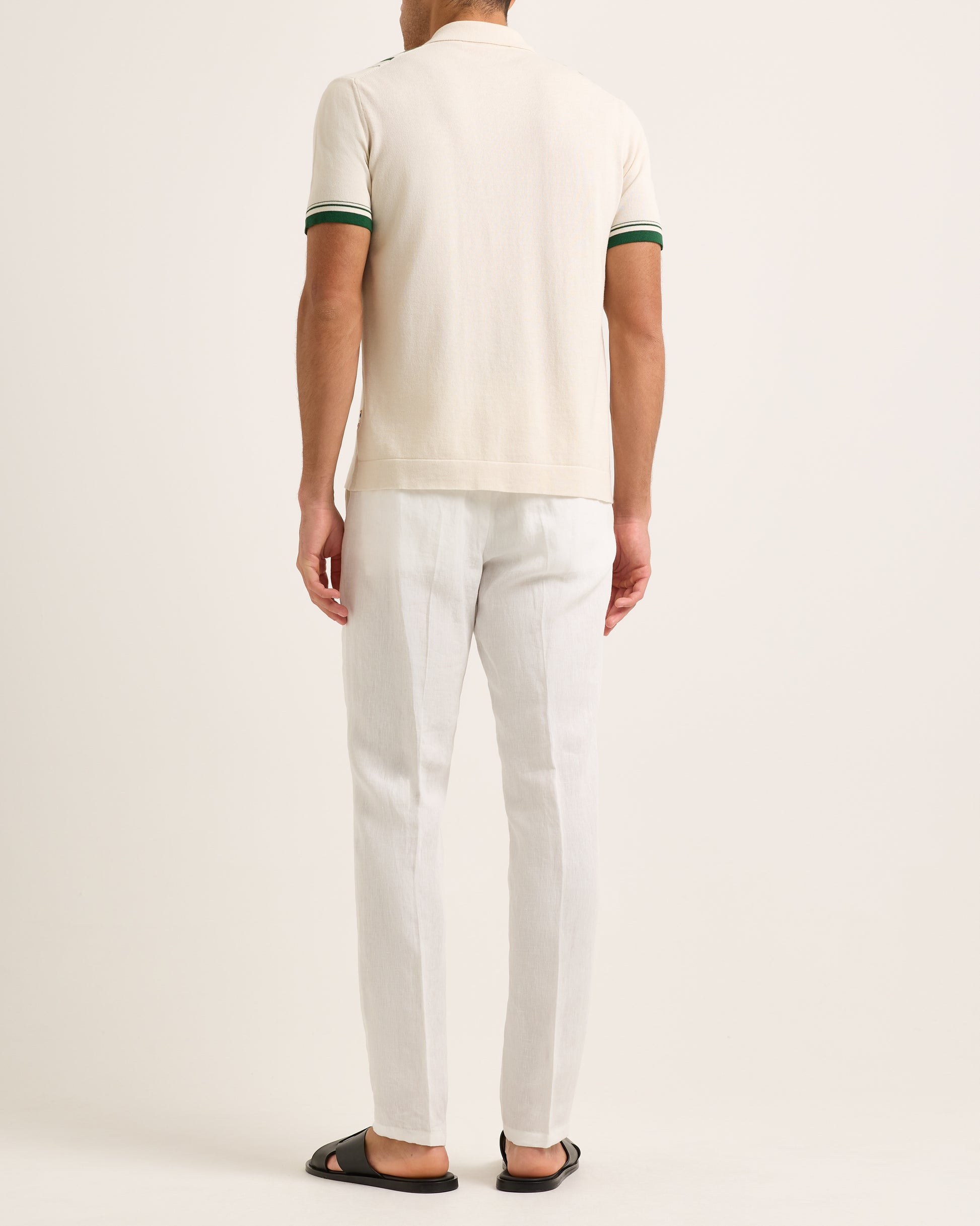 Model wearing a beige and green striped shirt with white trousers on a white background