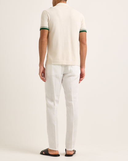 Model wearing a beige and green striped shirt with white trousers on a white background