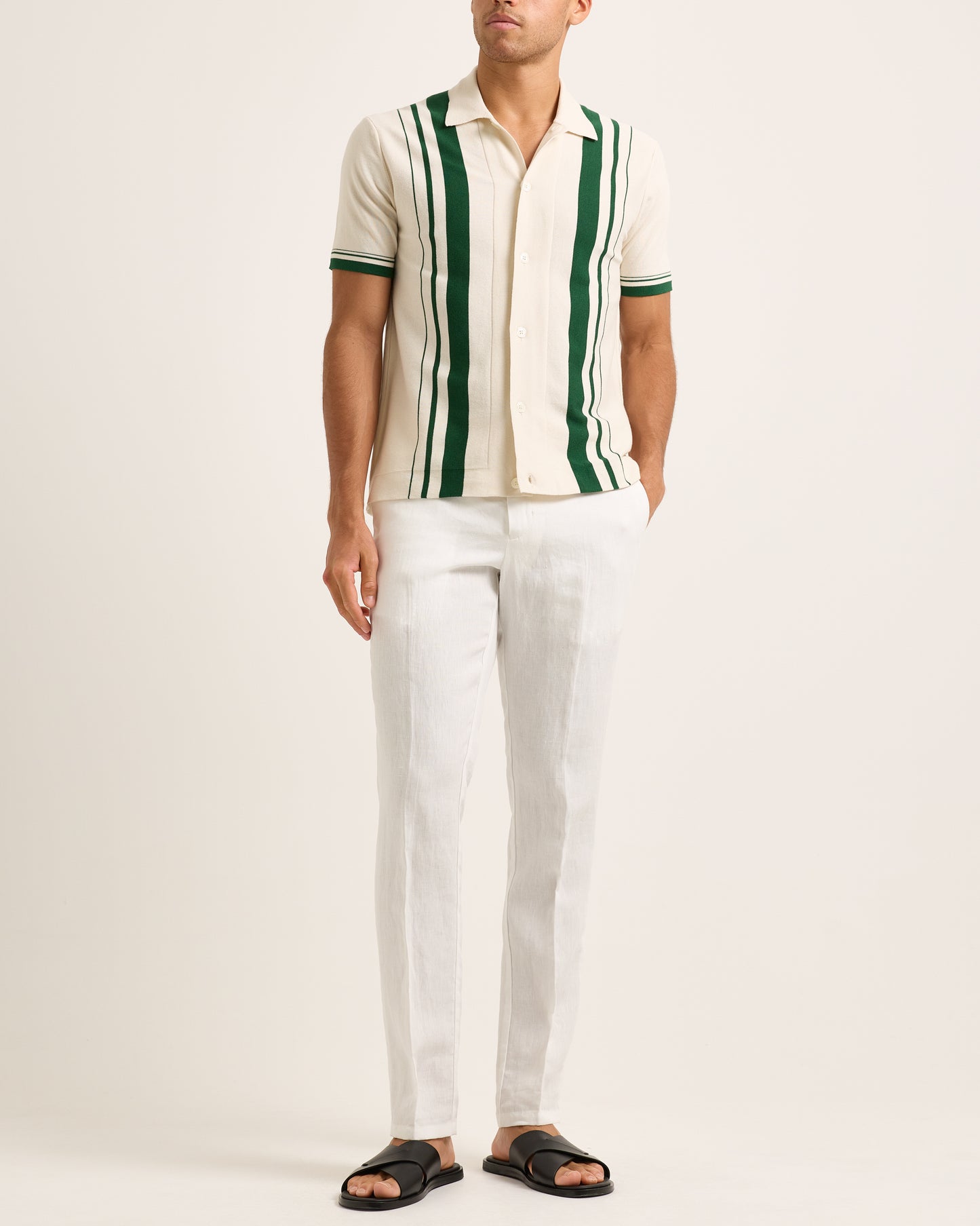 Model wearing a beige and green striped shirt with white trousers on a white background