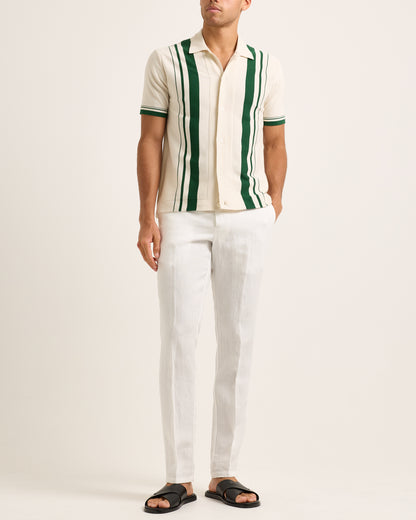 Model wearing a beige and green striped shirt with white trousers on a white background