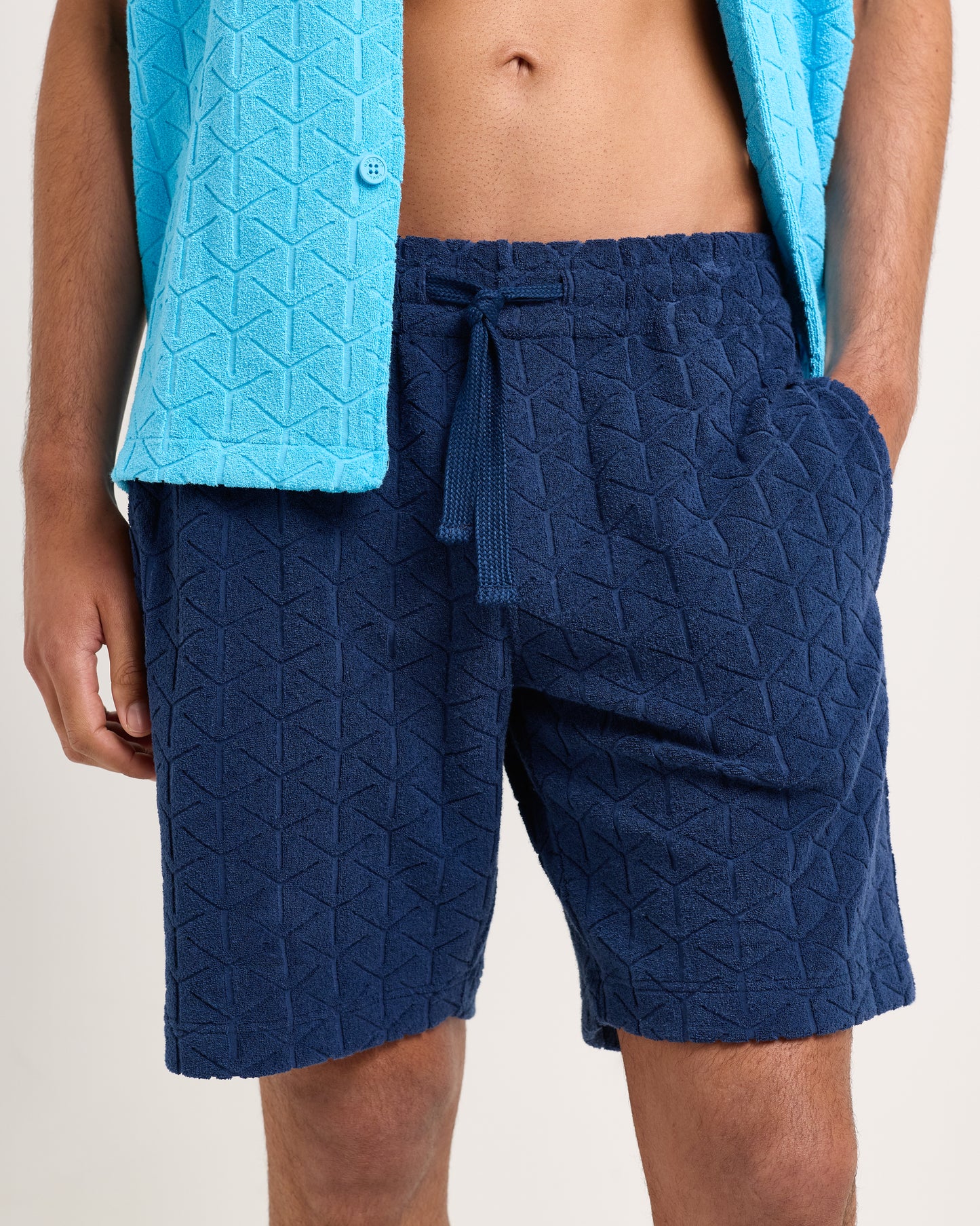 Person wearing blue quilted shorts and a matching jacket on a plain background
