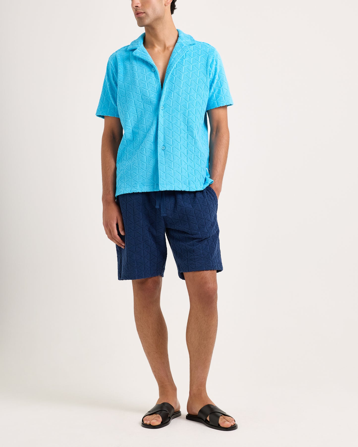 Man wearing a blue shirt and shorts on a white background