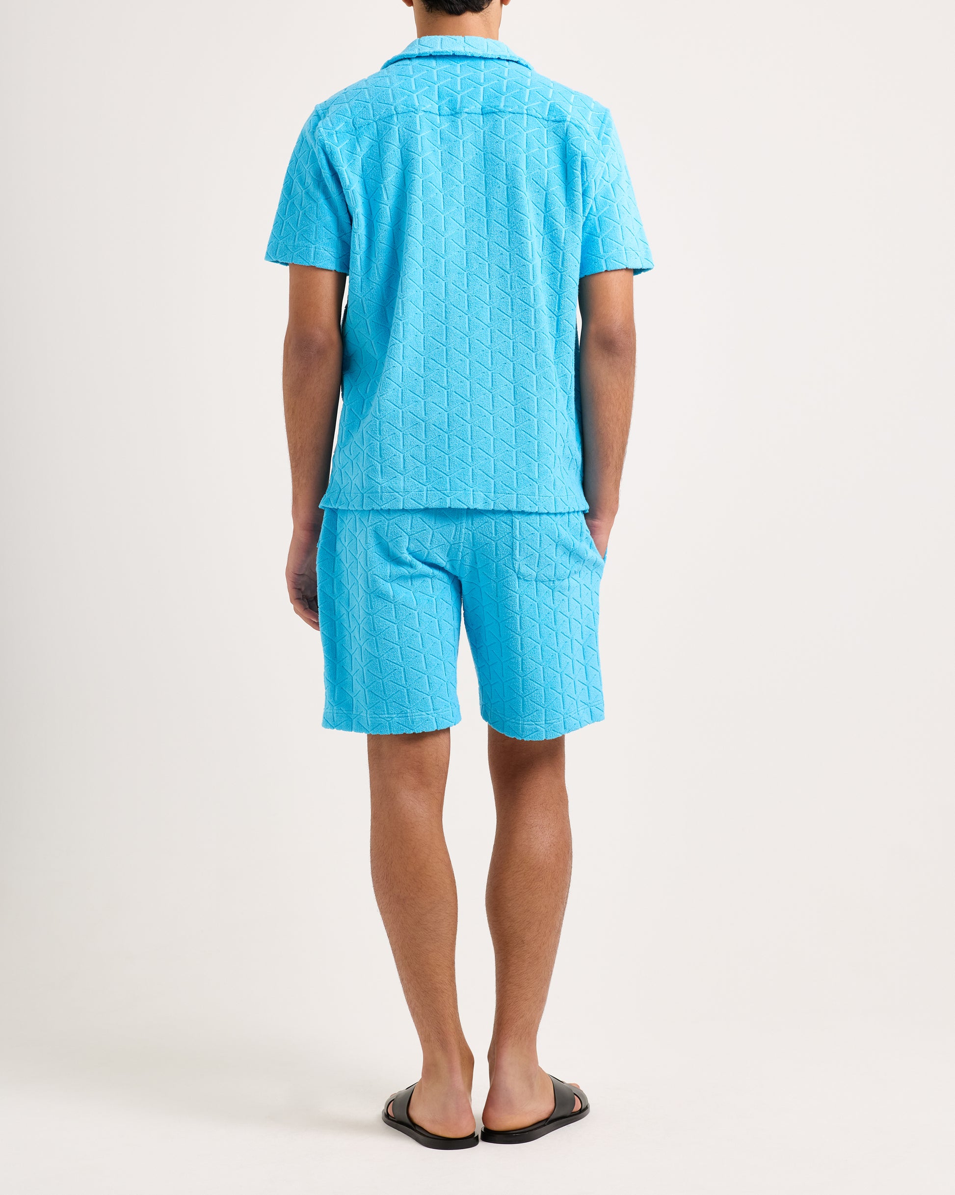 Person wearing a blue textured shirt and shorts set on a white background