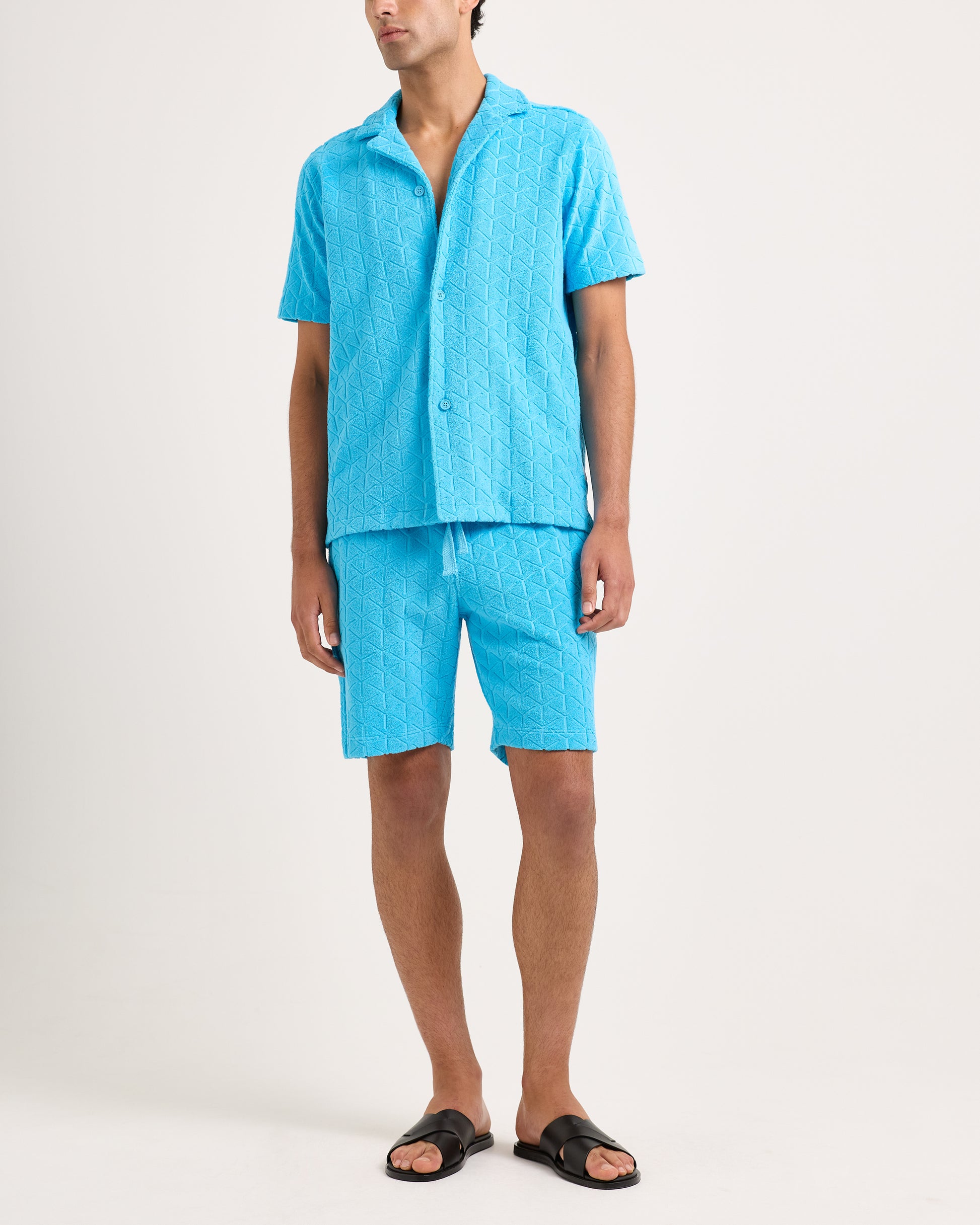 Person wearing a blue textured shirt and shorts set on a white background