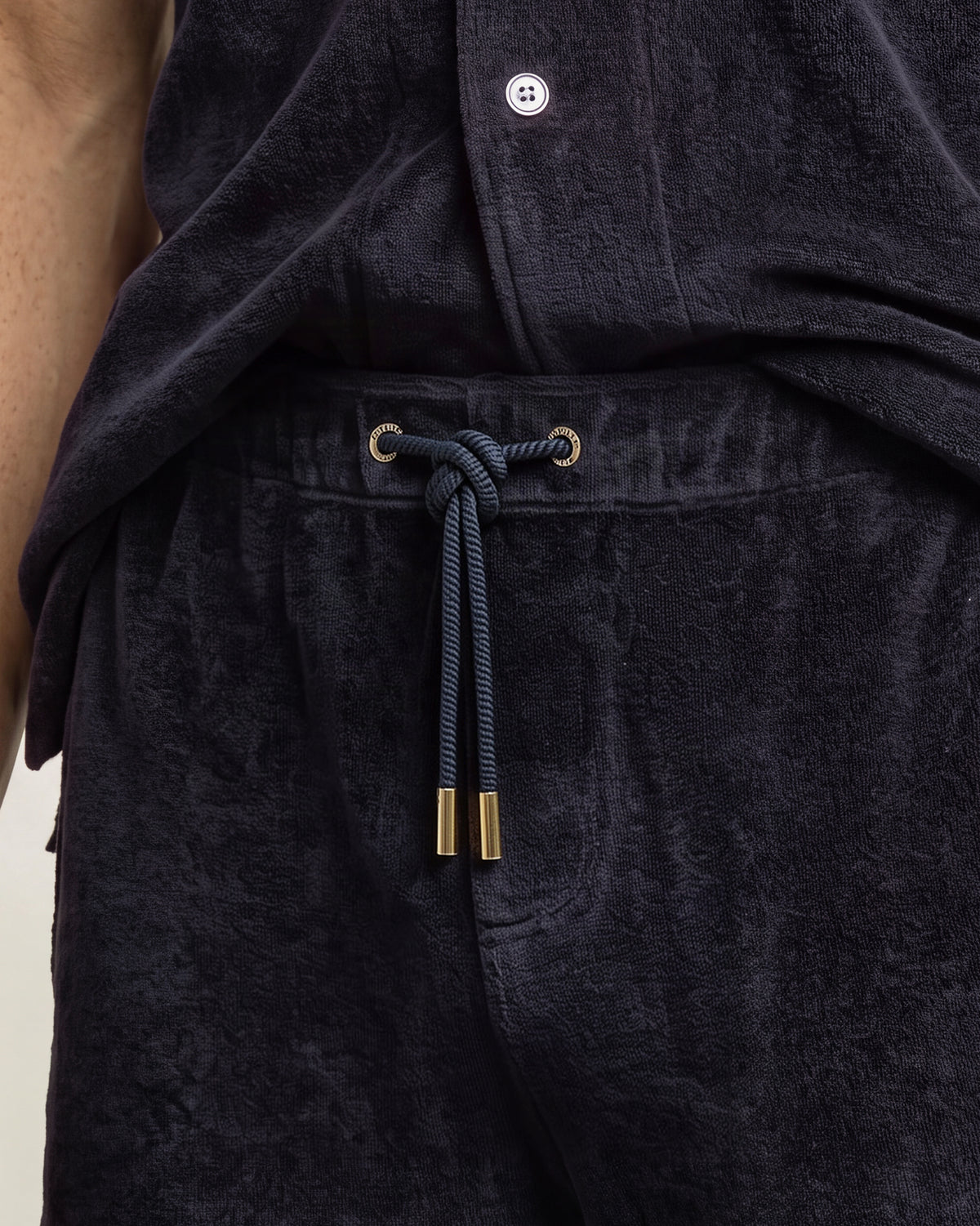 Closeup of navy towelling drawcord sweat shorts, with gold detailing on the drawcord
