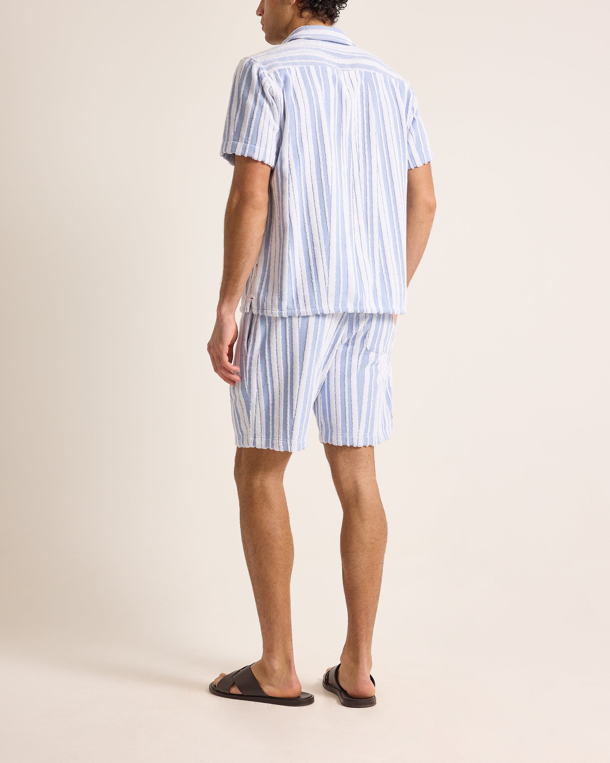 Person wearing a blue and white striped set on a beige background