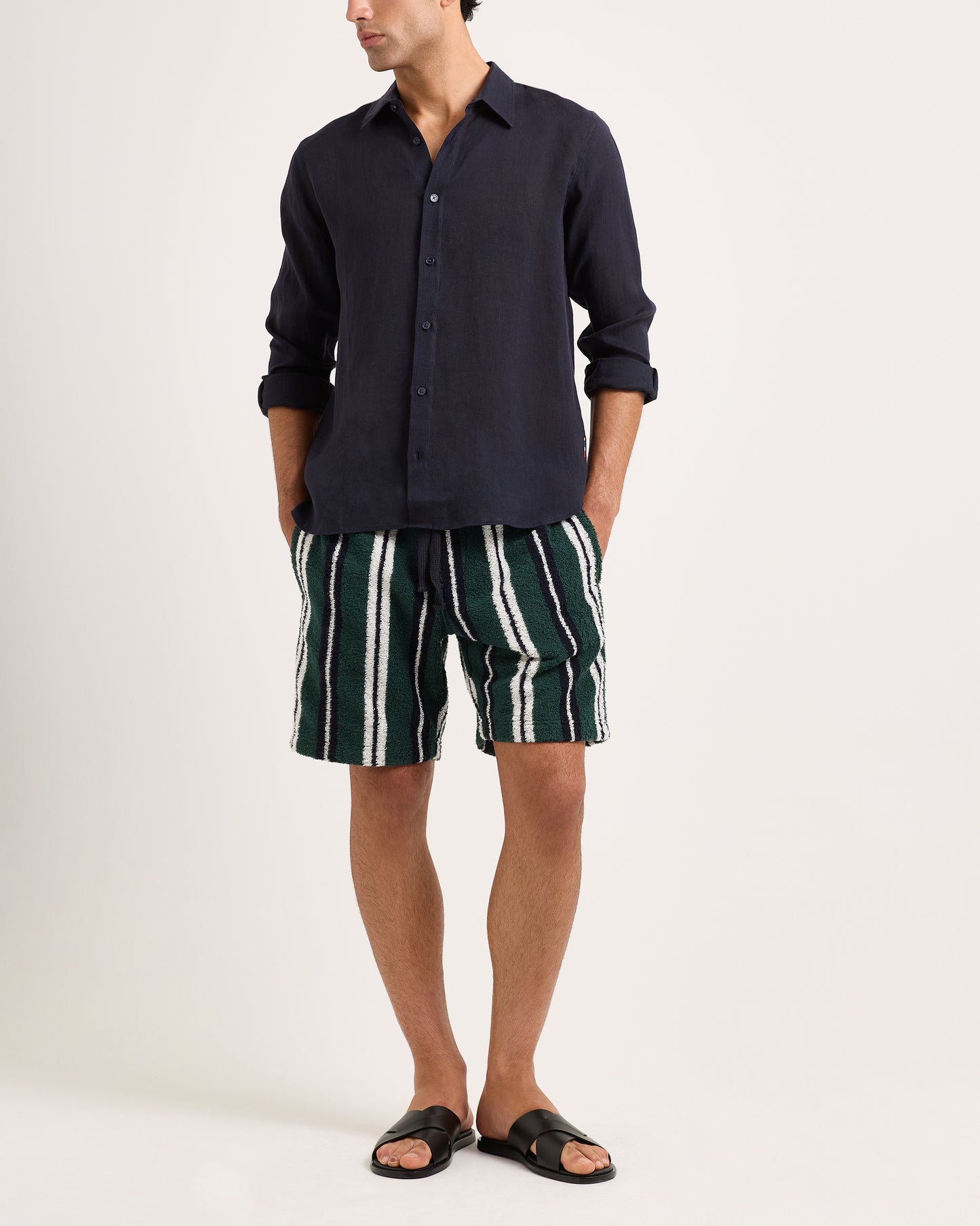 Model wearing green, white and black towelling striped shorts with a navy shirt on a white background
