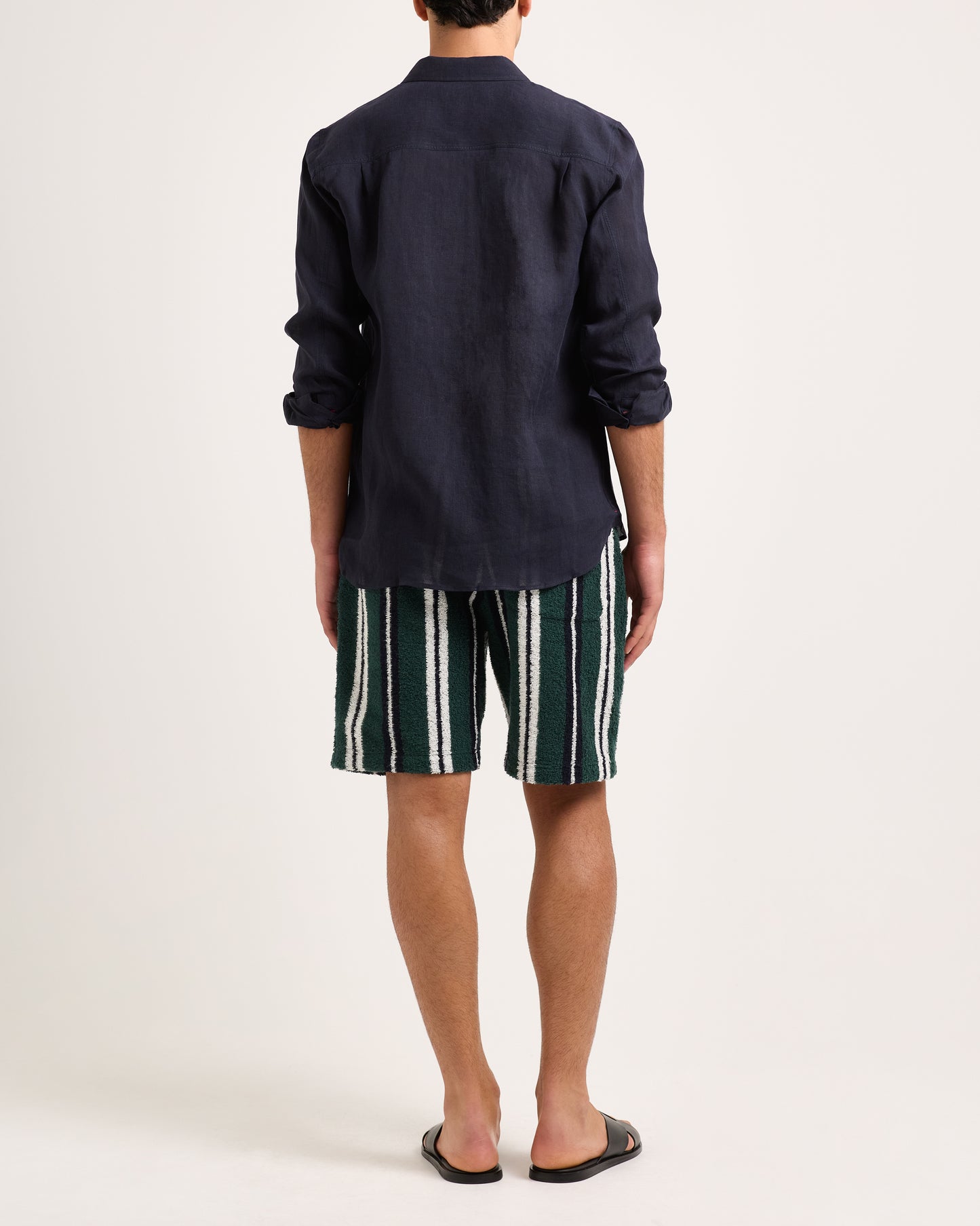 Model wearing green, white and black towelling striped shorts with a navy shirt on a white background