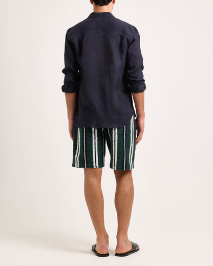 Model wearing green, white and black towelling striped shorts with a navy shirt on a white background