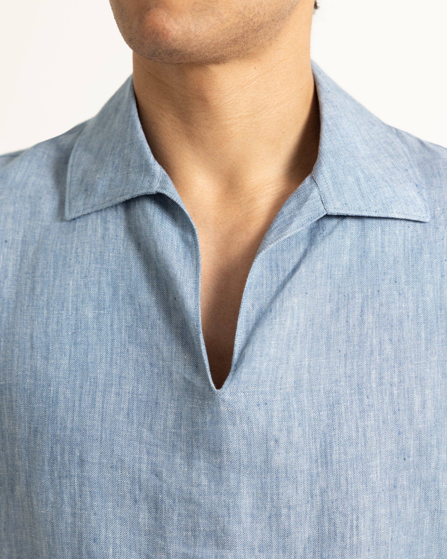 Close-up of a person wearing a light blue shirt with a collar.