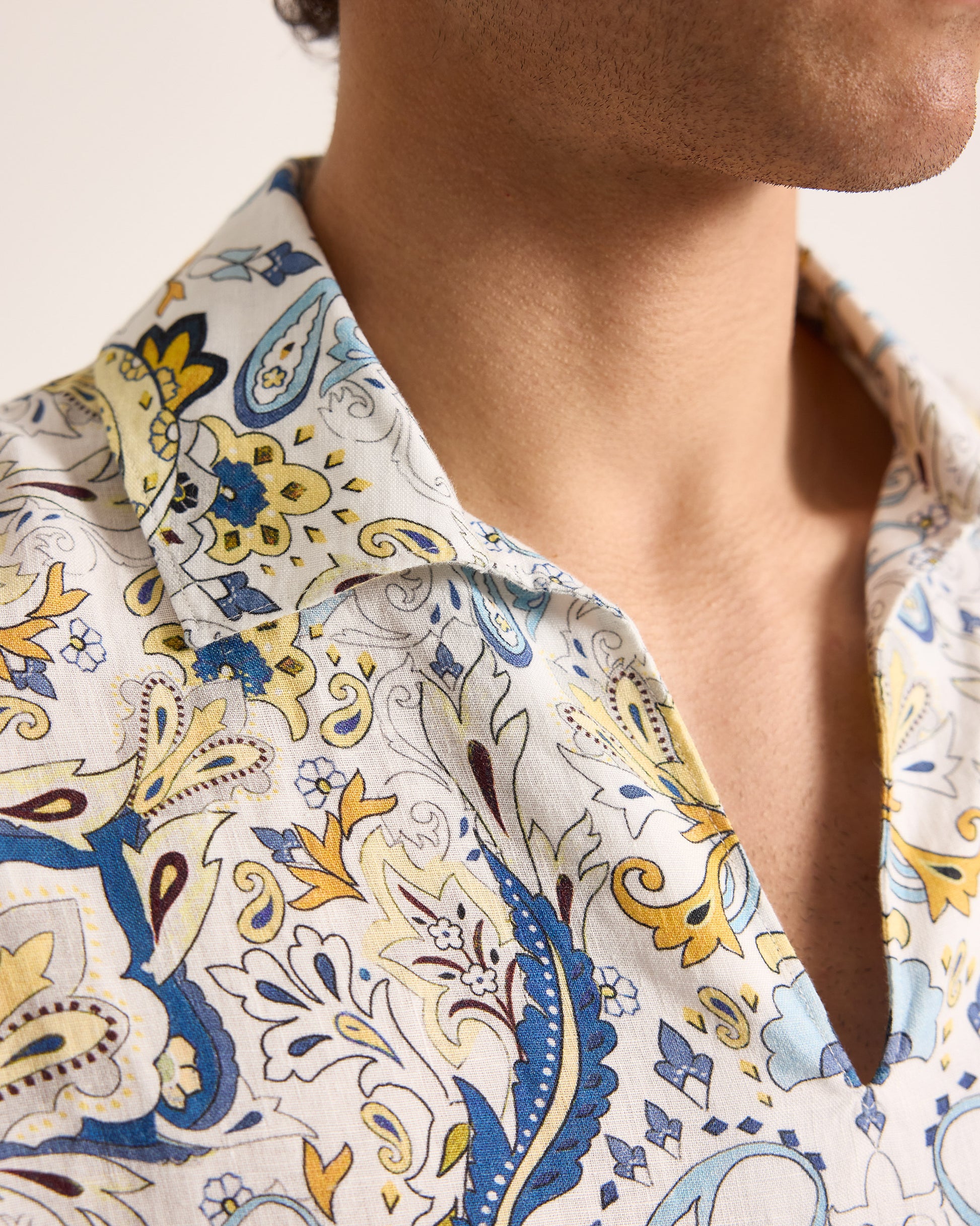 Close-up of a person wearing a patterned shirt with blue, yellow, and white colors.
