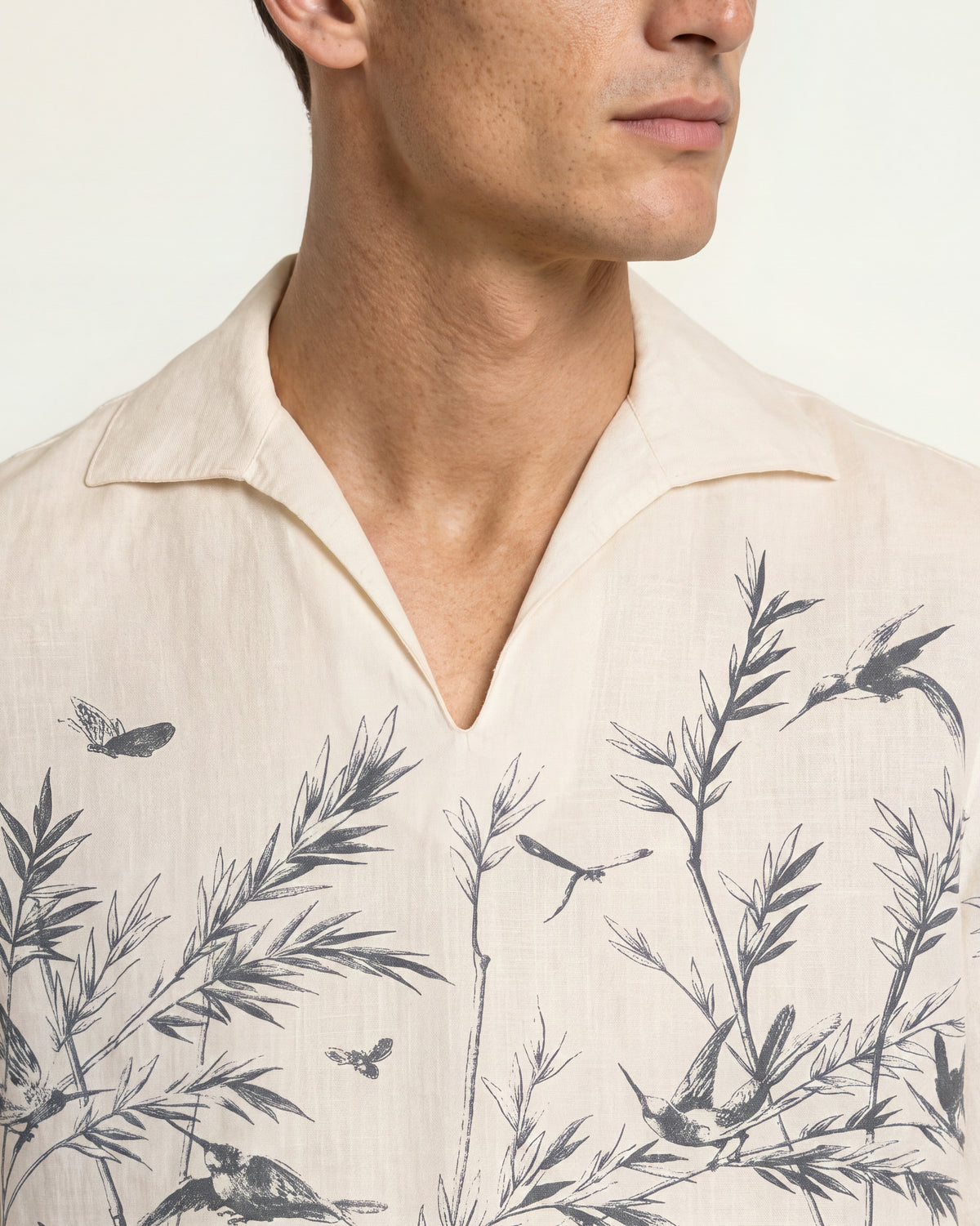 Closeup of white overhead shirt with black botanical print on a plain background