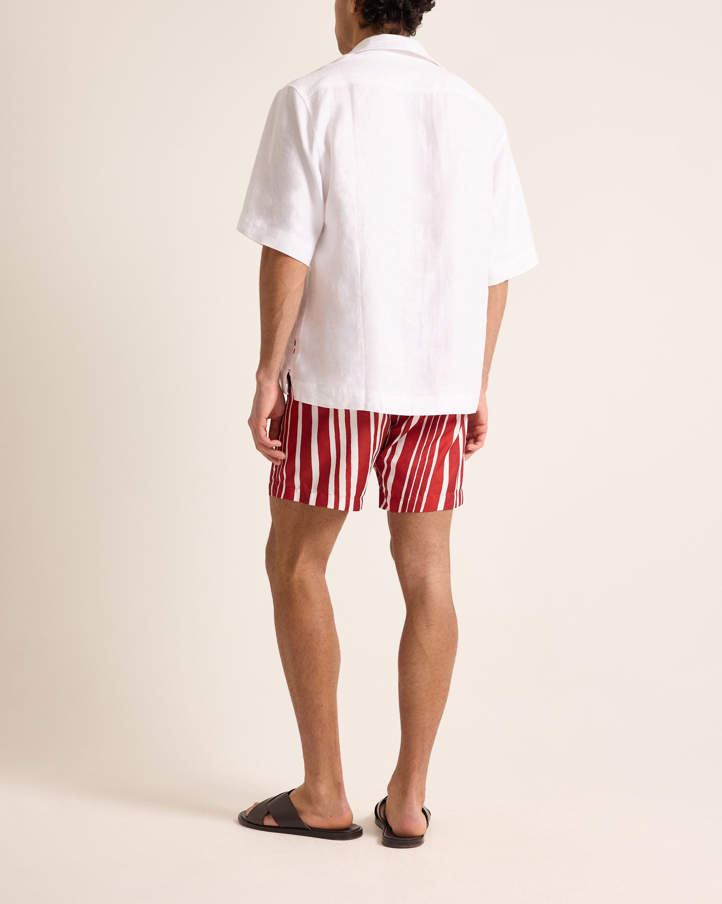 Person wearing a white shirt and red striped shorts on a plain background