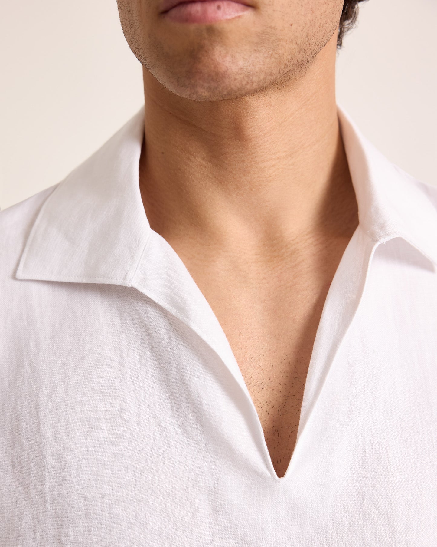 Close-up of a person wearing a white shirt with a neutral background