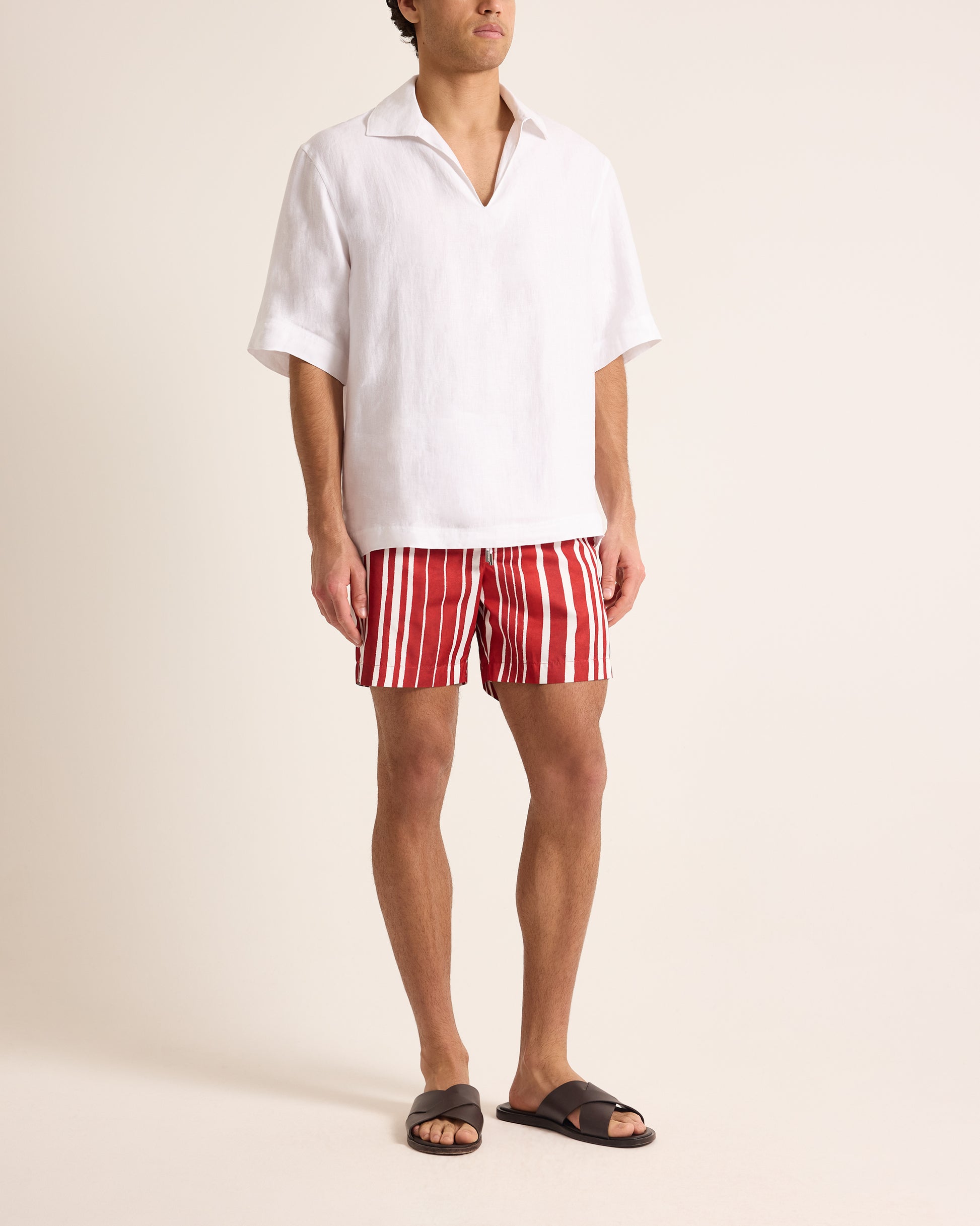 Person wearing a white shirt and red and white striped shorts on a plain background