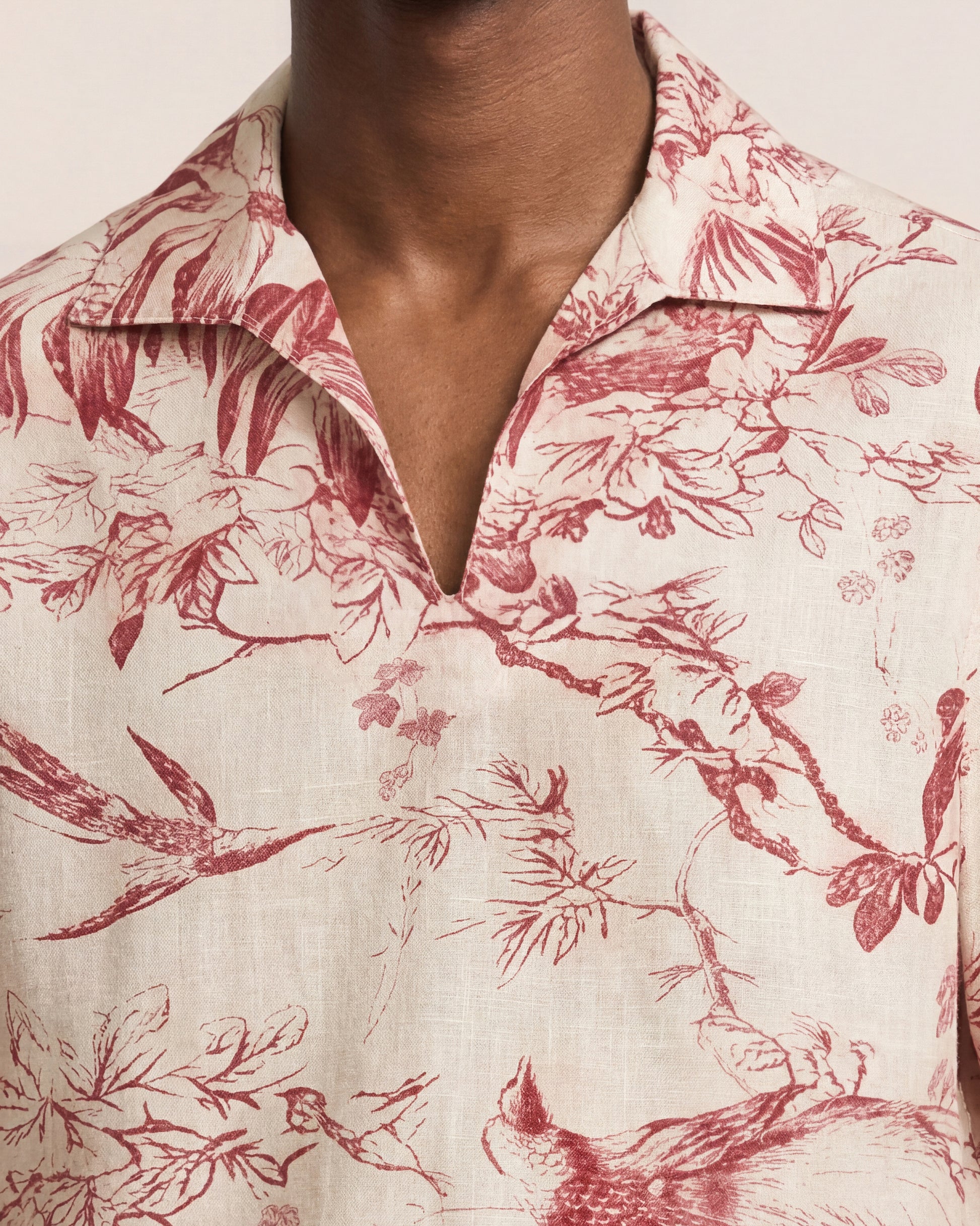 Close-up of a person wearing a floral patterned shirt with red and green colors.