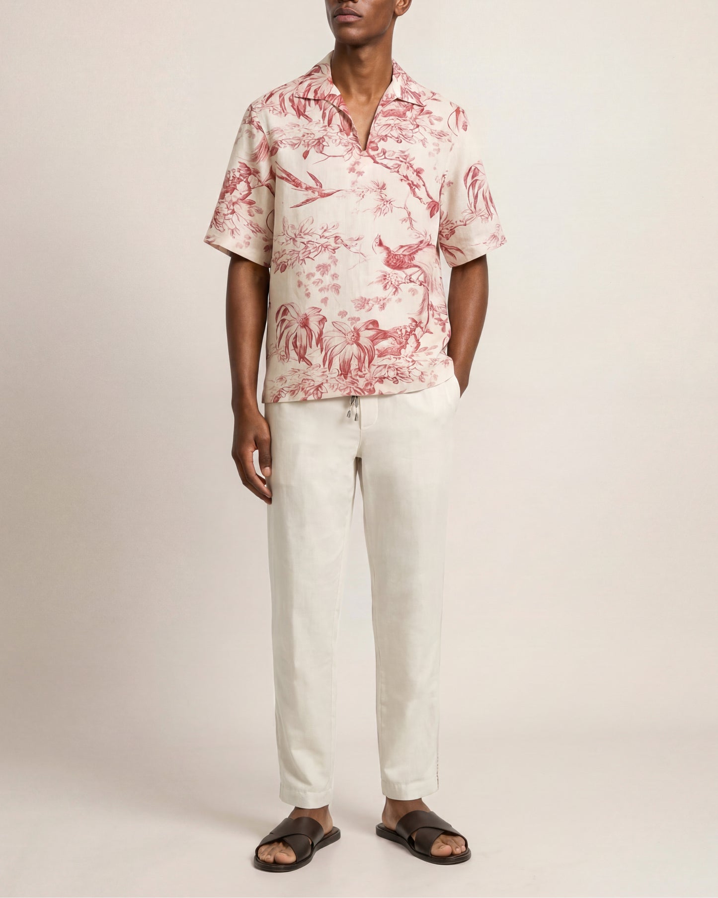 Man wearing a red and white patterned shirt with white pants on a plain background