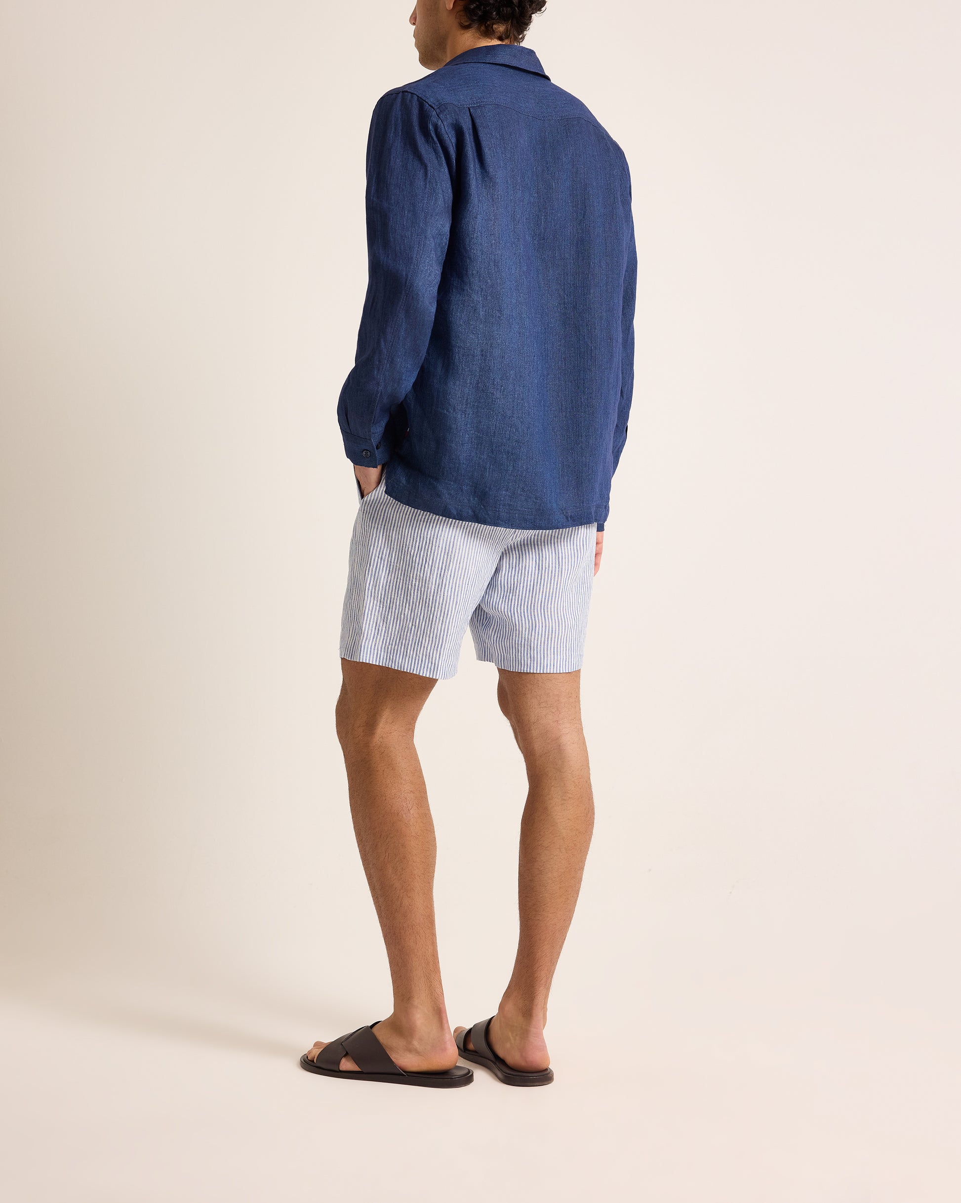 Person wearing a blue shirt and light blue shorts on a beige background