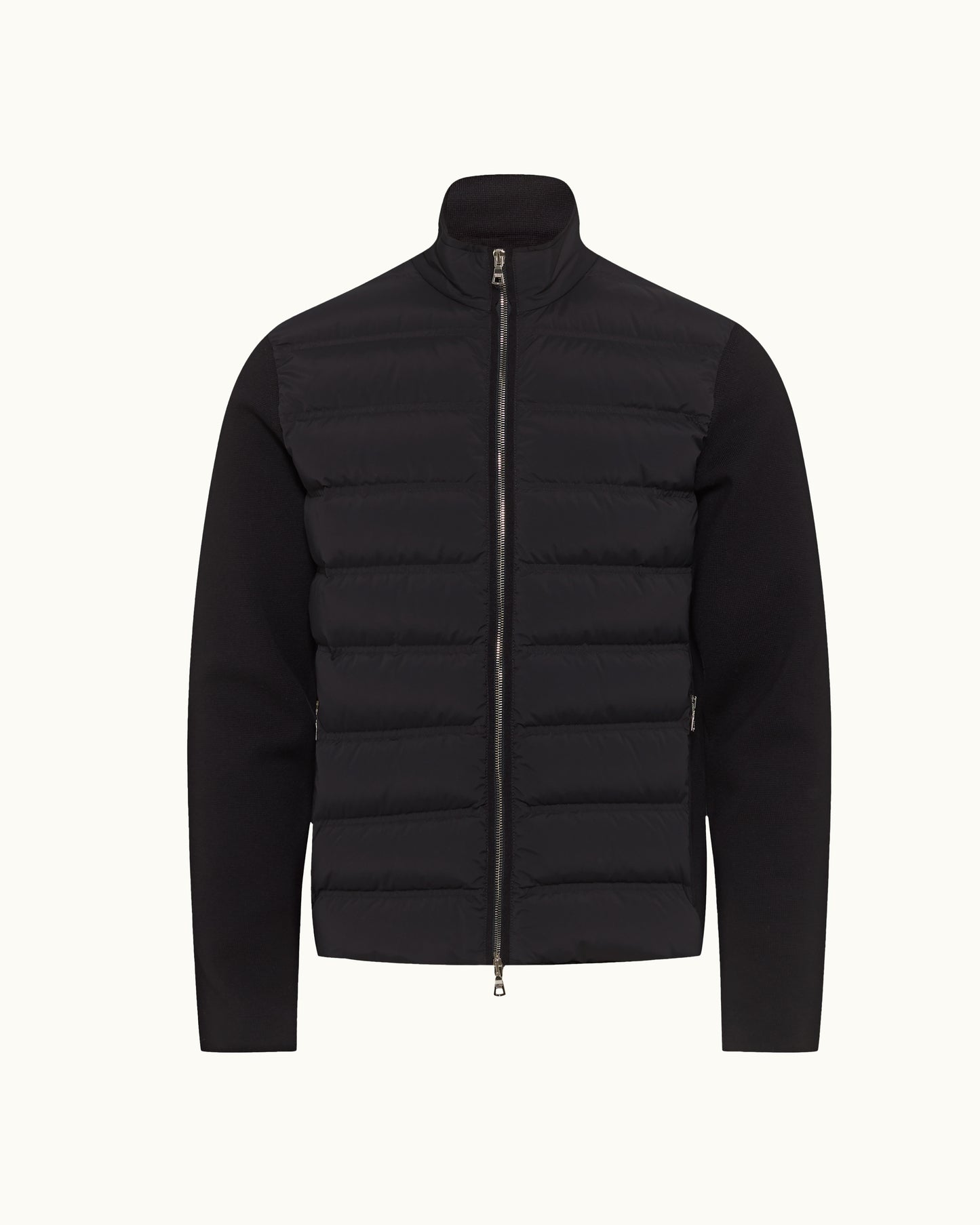 A black hybrid jacket featuring a quilted puffer vest body with horizontal baffles and solid long sleeves, shown on a light off-white background.