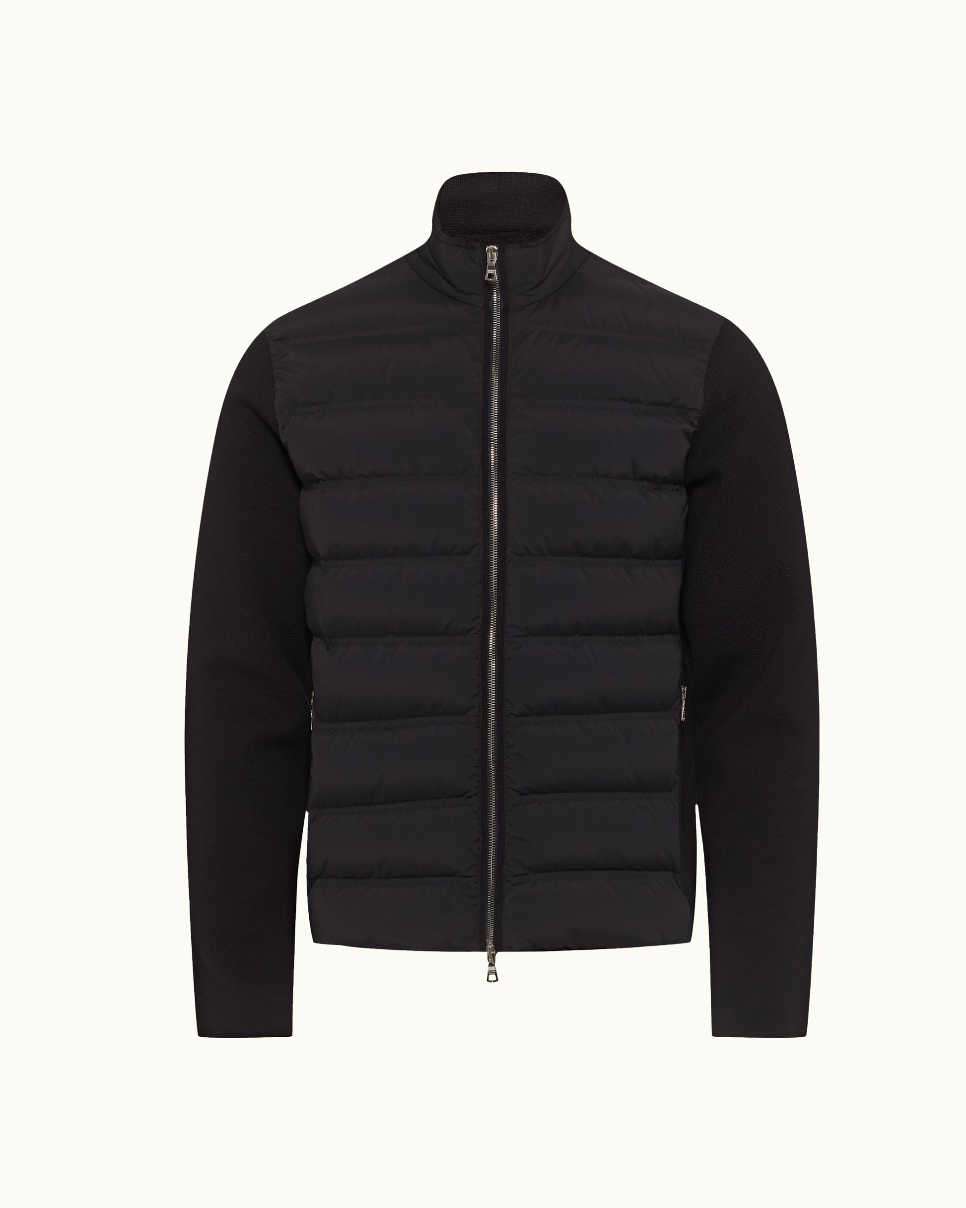A black hybrid jacket featuring a quilted puffer vest body with horizontal baffles and solid long sleeves, shown on a light off-white background.