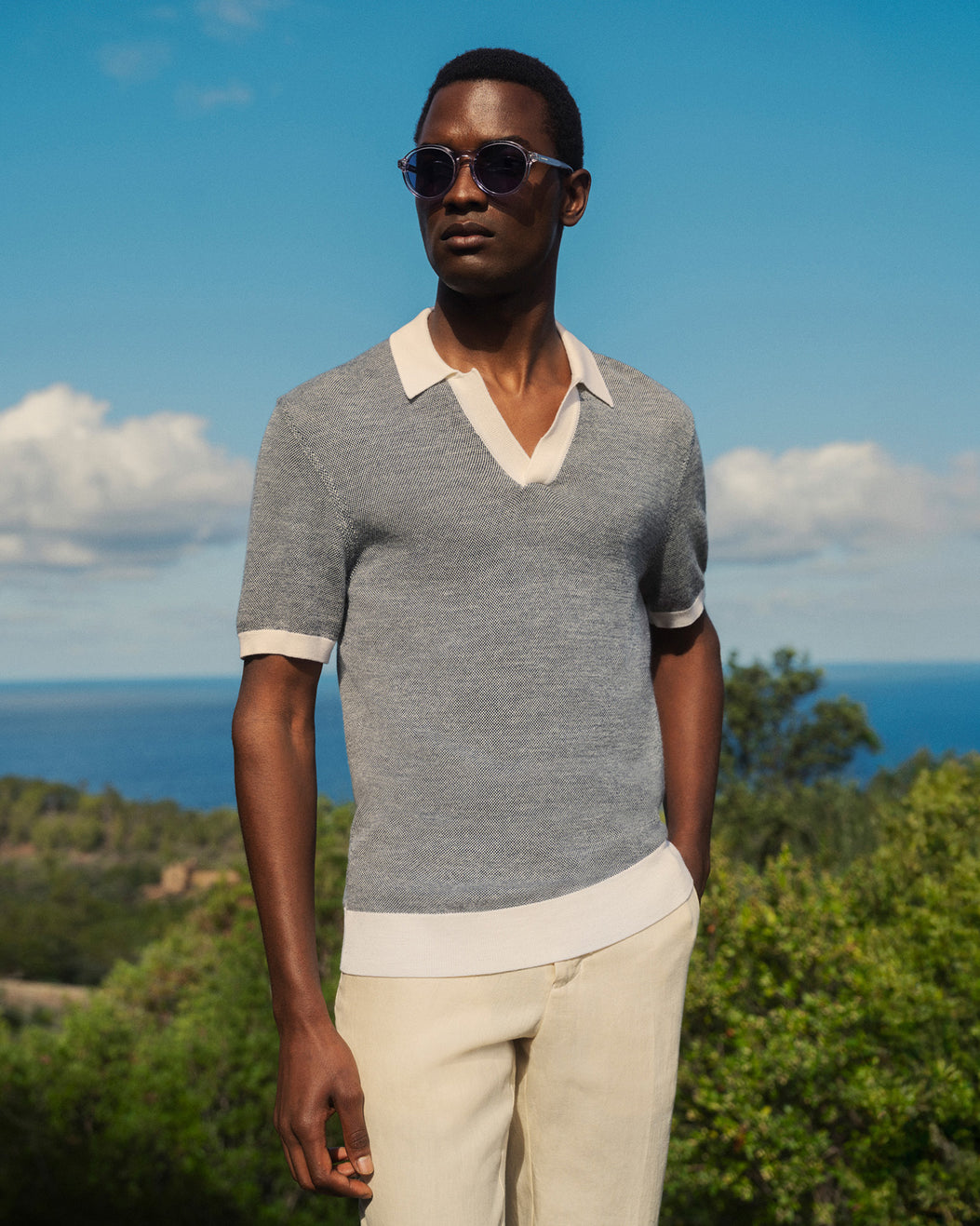 Man wearing sunglasses and a gray polo shirt with a scenic background
