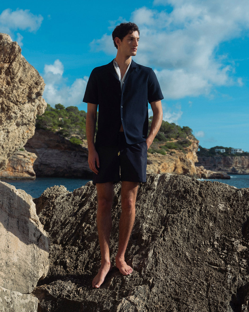 Man standing on rocky cliffs with a scenic ocean view