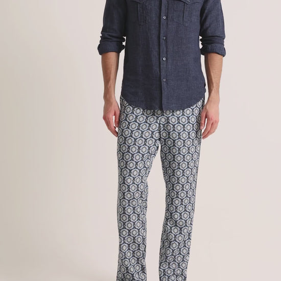 Man wearing printed blue trousers with navy linen shirt on a plain background
